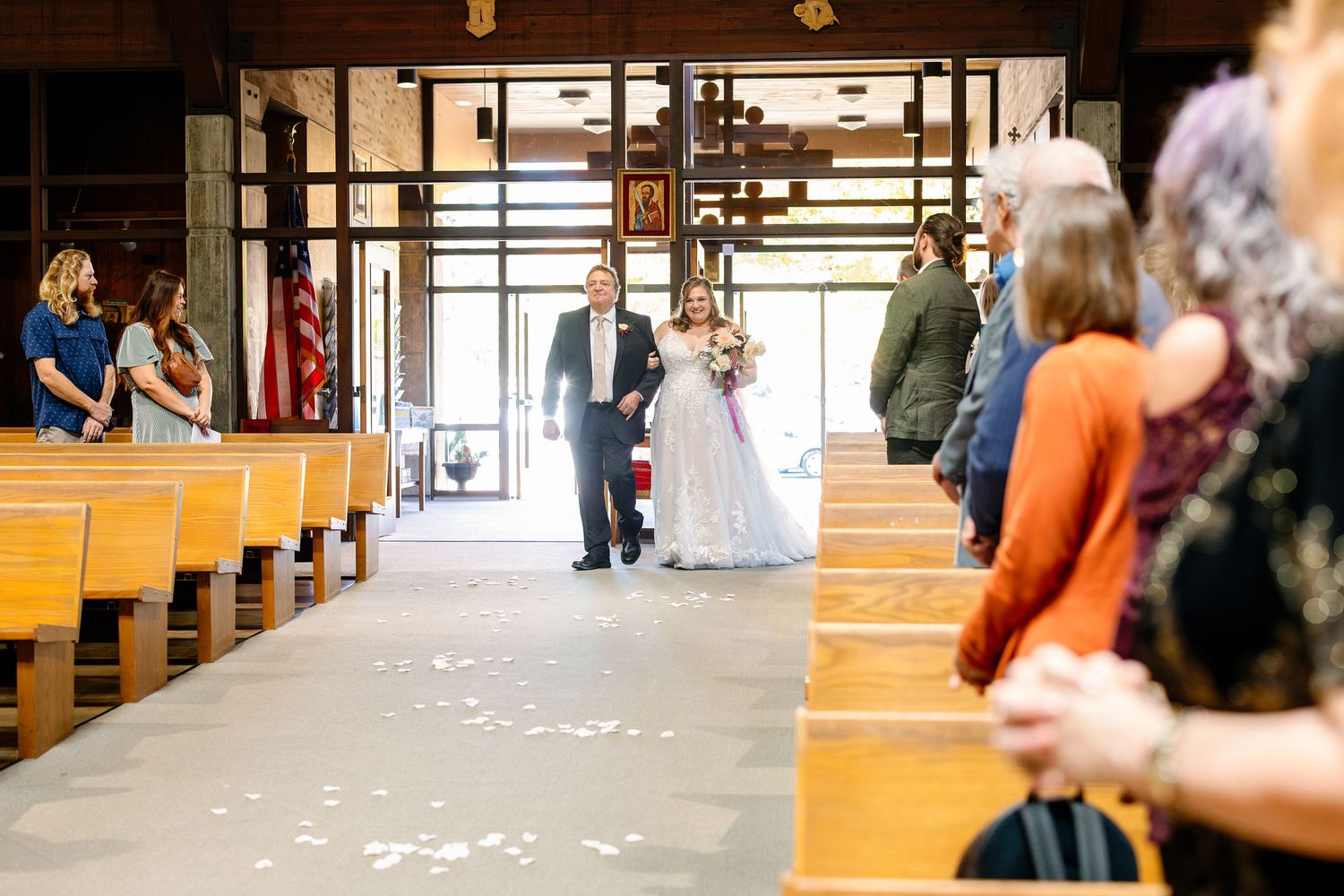 Wedding ceremony aisle decorated with white petals and gold accents in an elegant indoor venue.