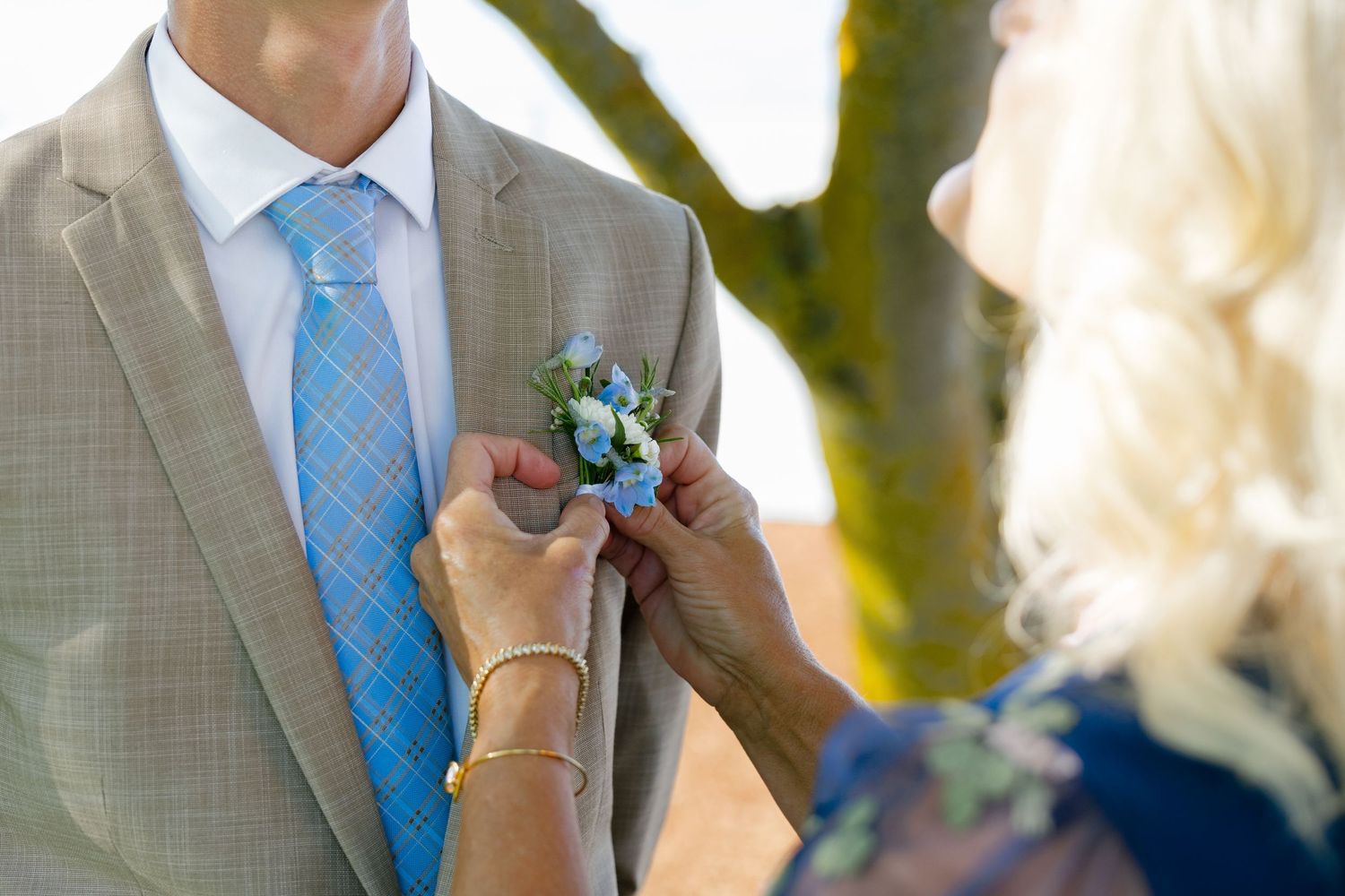 A wedding couple's formal attire detail showing light blue tie and floral boutonniere.