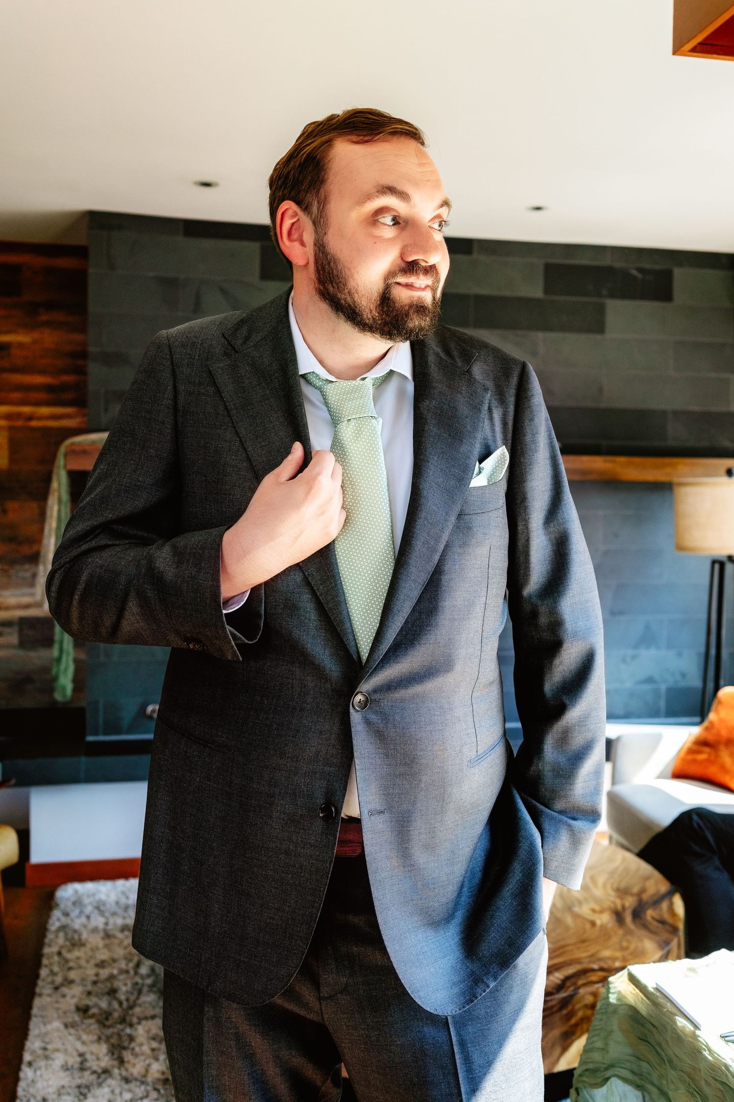 Man in navy suit and mint green tie poses in series of candid shots showing different angles and expressions.