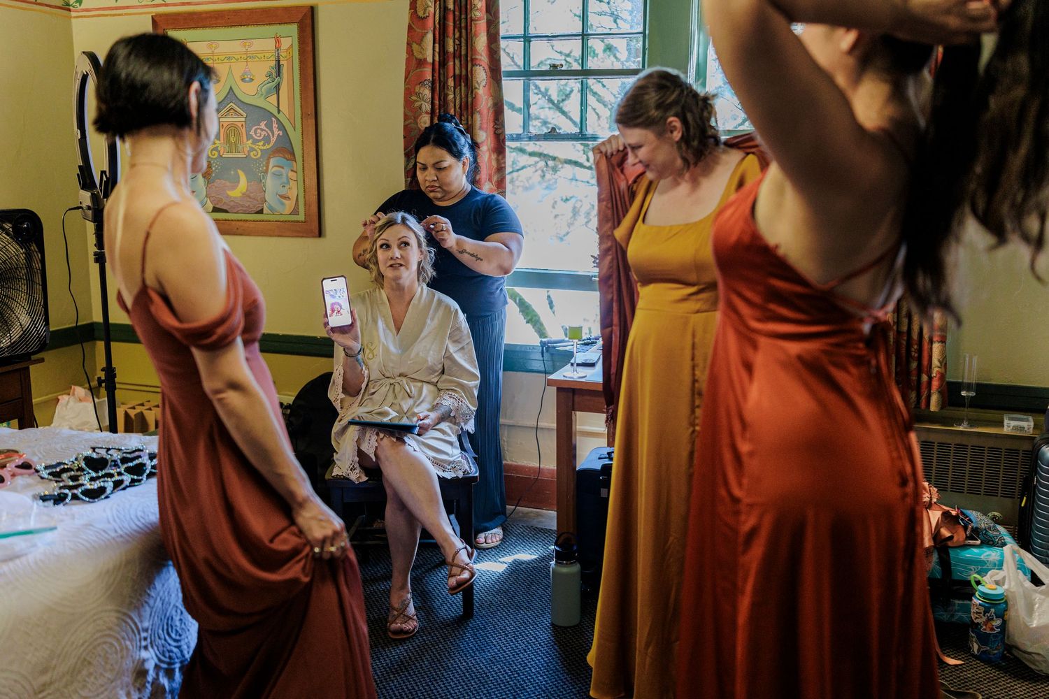 Wedding party members in burgundy dresses gathered in a room during pre-ceremony preparations.