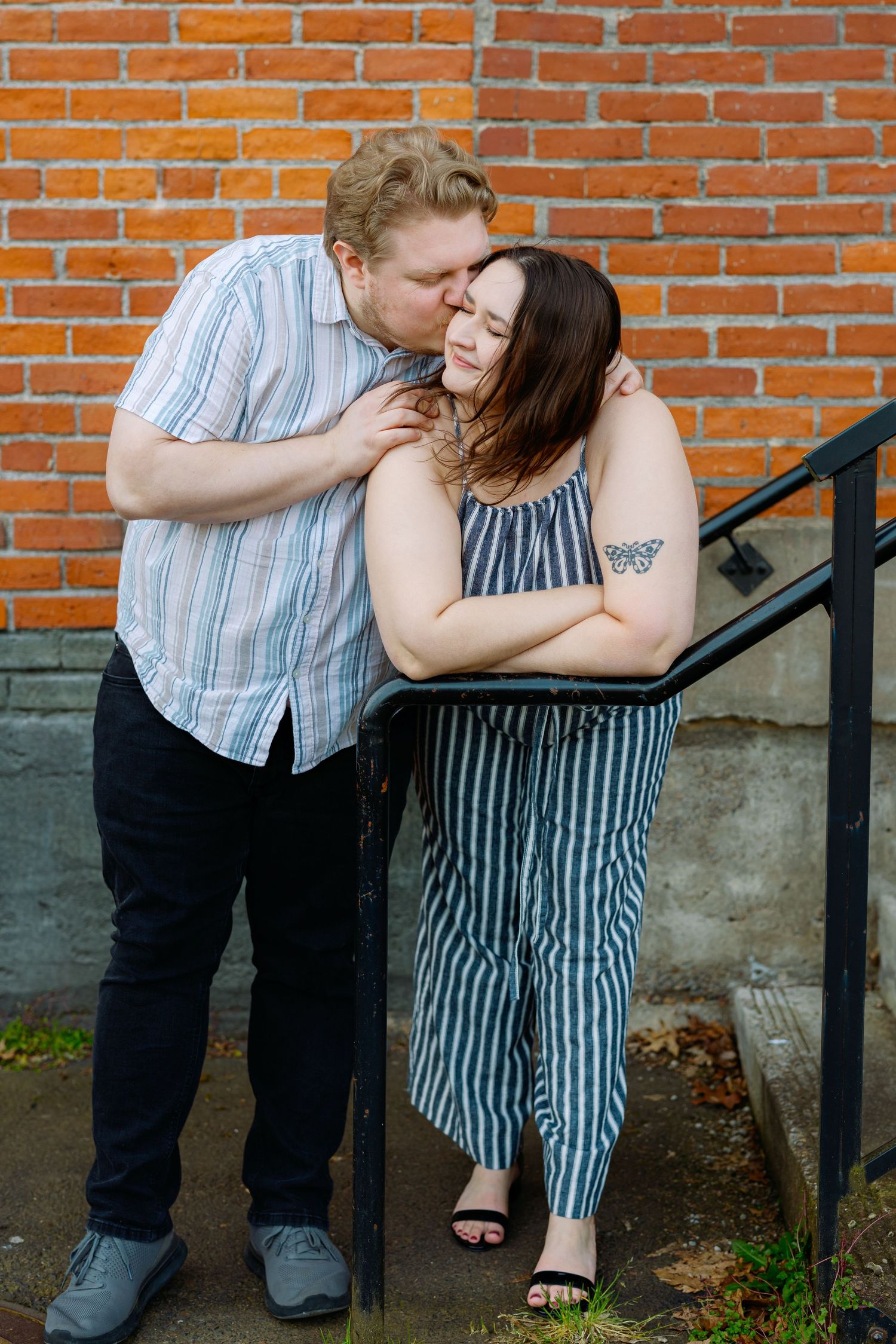 A couple shares intimate moments against a red brick wall background in a series of candid photos.