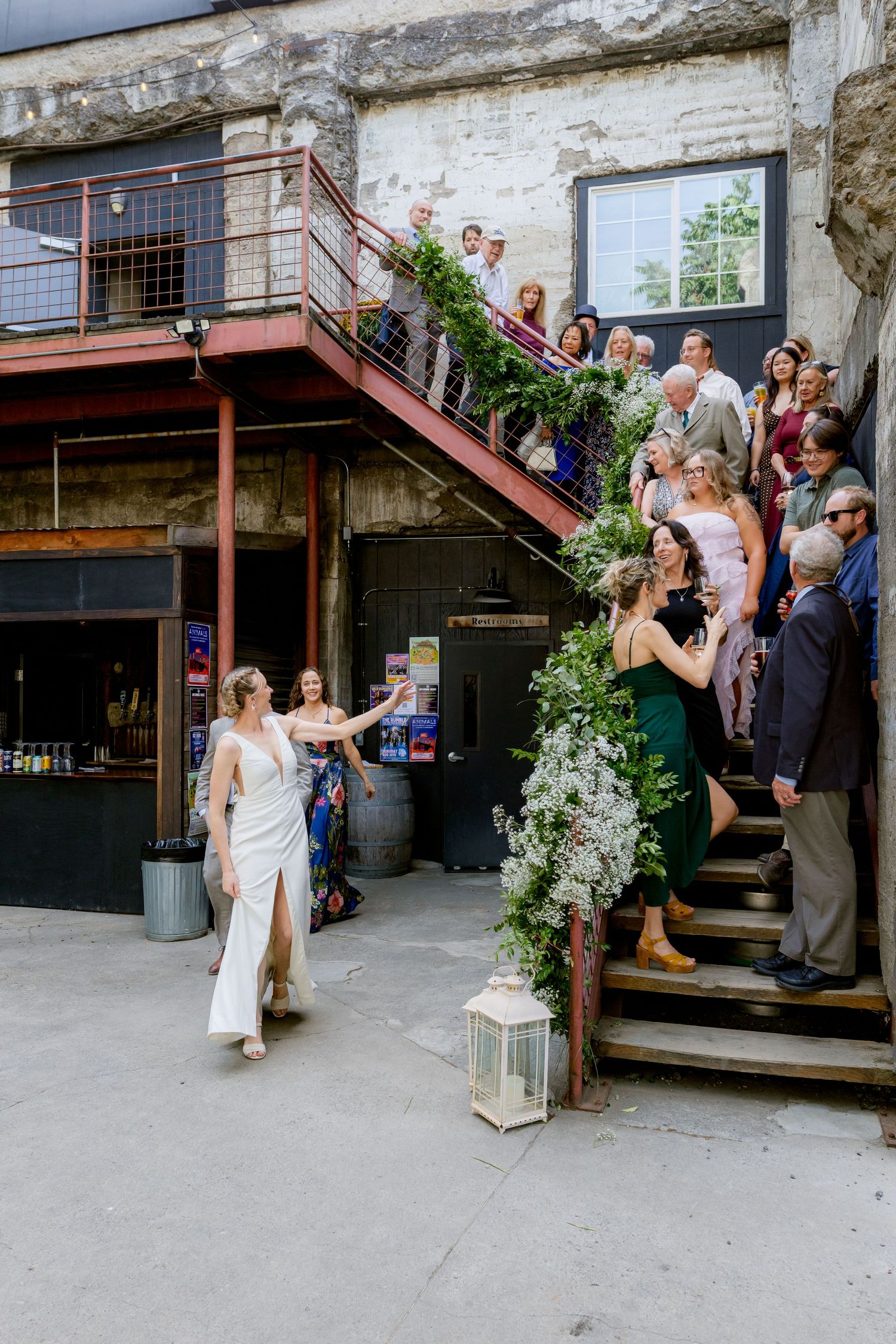 Bride walking past guests on industrial staircase.