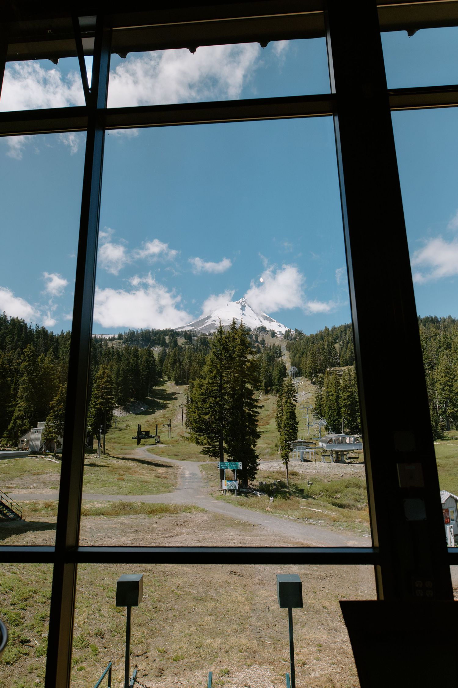 Stunning view of snow-capped Mt. Hood framed by large windows at Mt. Hood Meadows resort in summer.