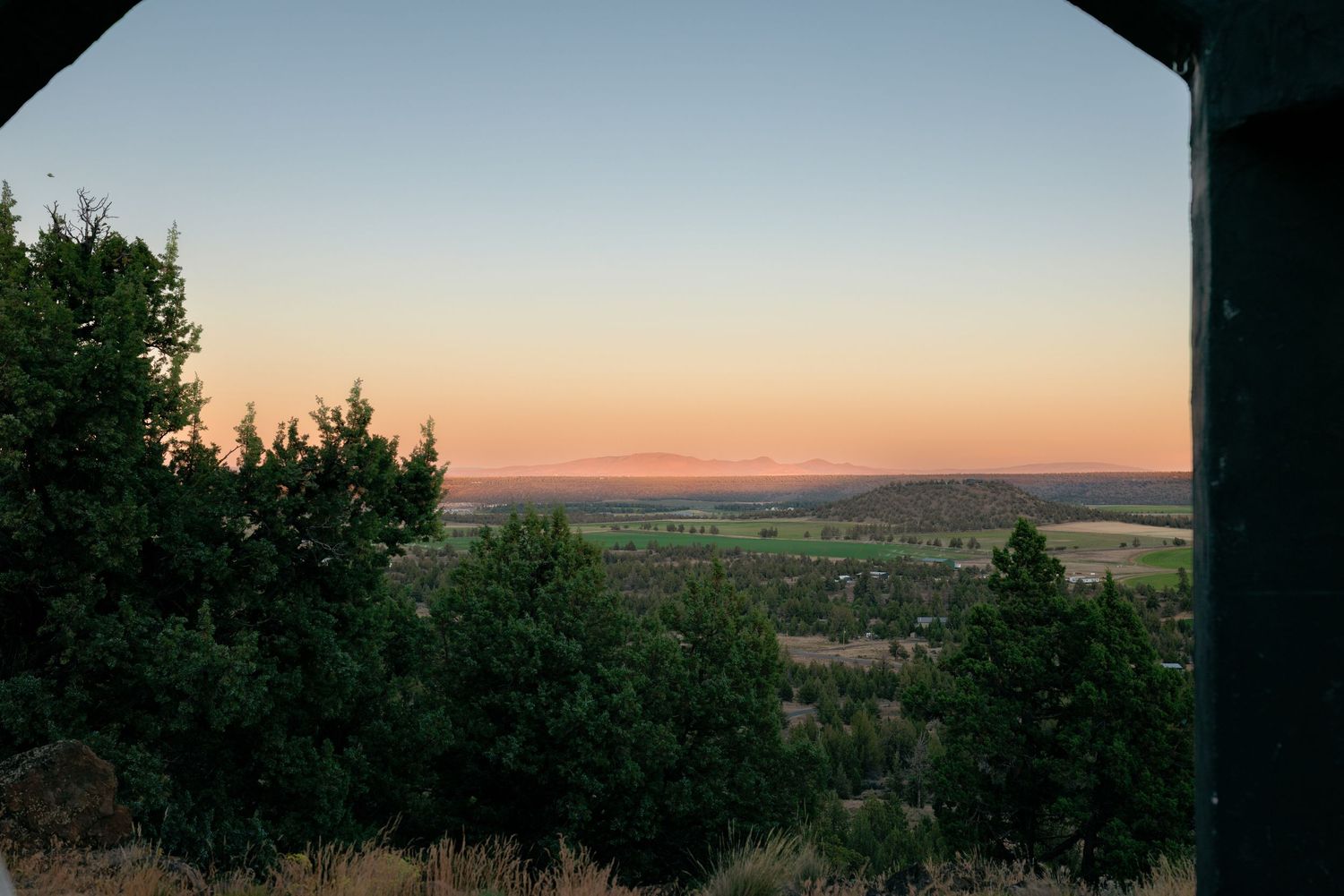 Stunning sunset panoramic view of a valley framed by evergreen trees at a wedding venue.
