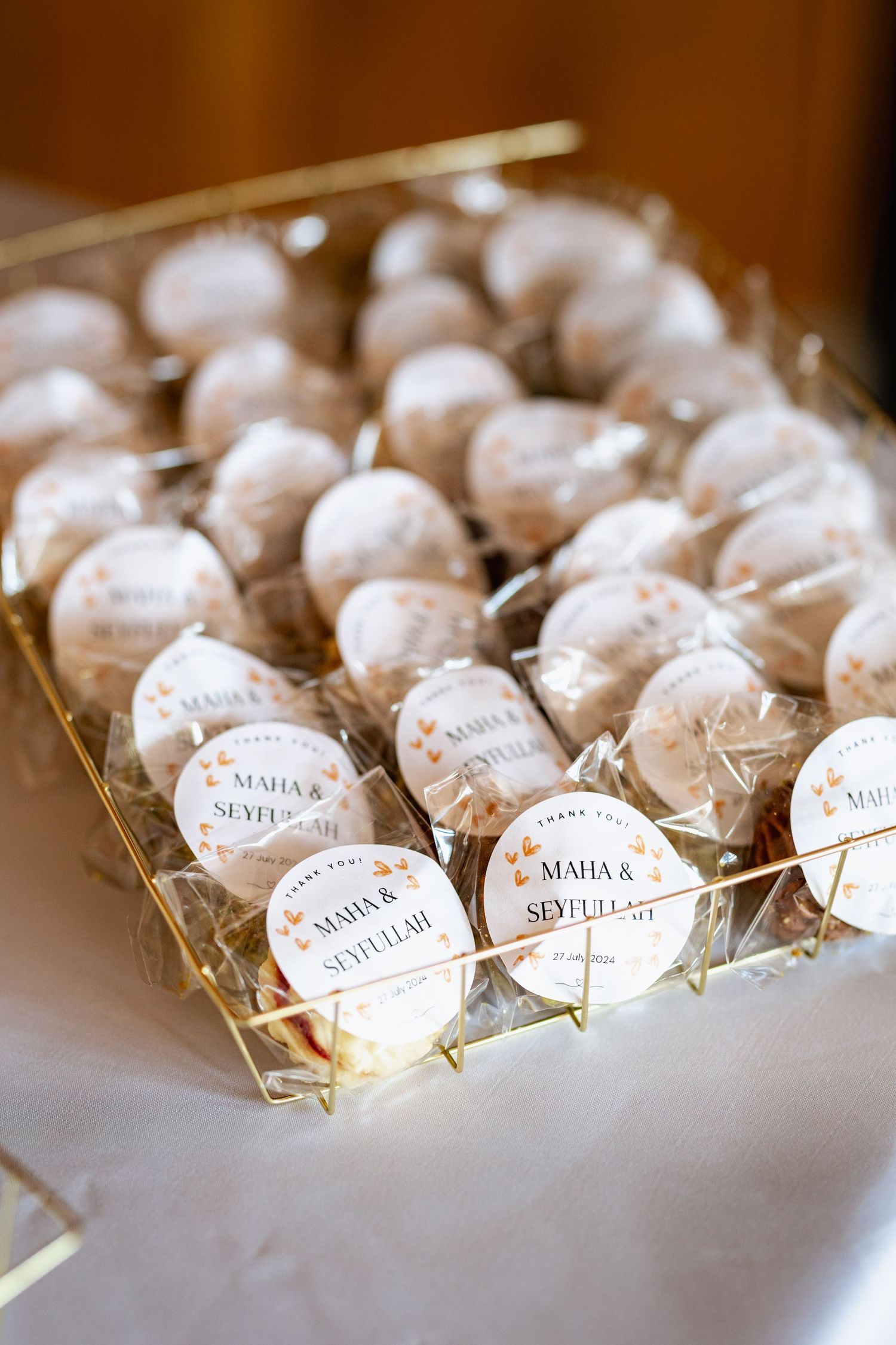 White powdered wedding favor cookies arranged in a gold tray with personalized name tags.