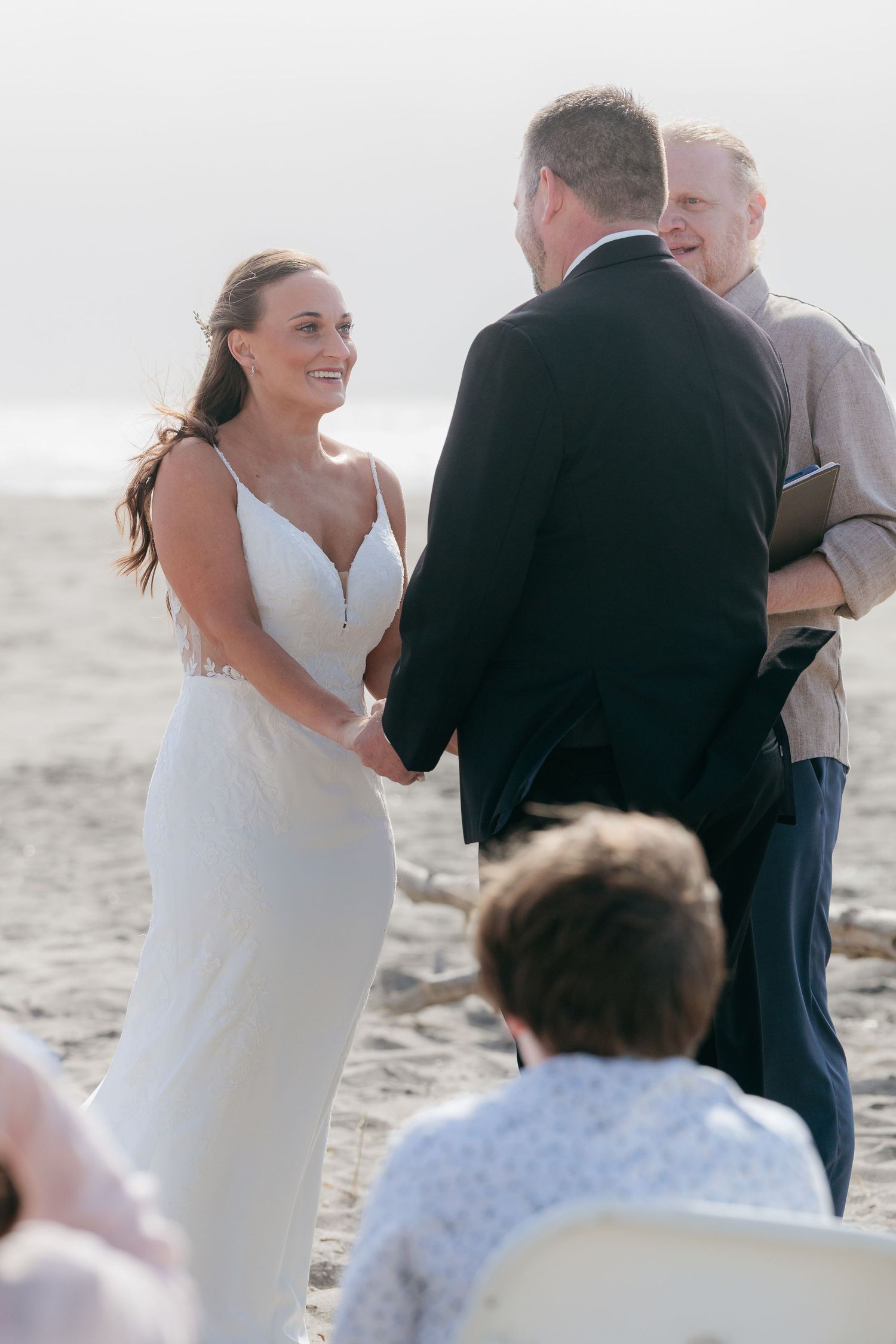 A beach wedding ceremony takes place against a misty oceanfront backdrop.