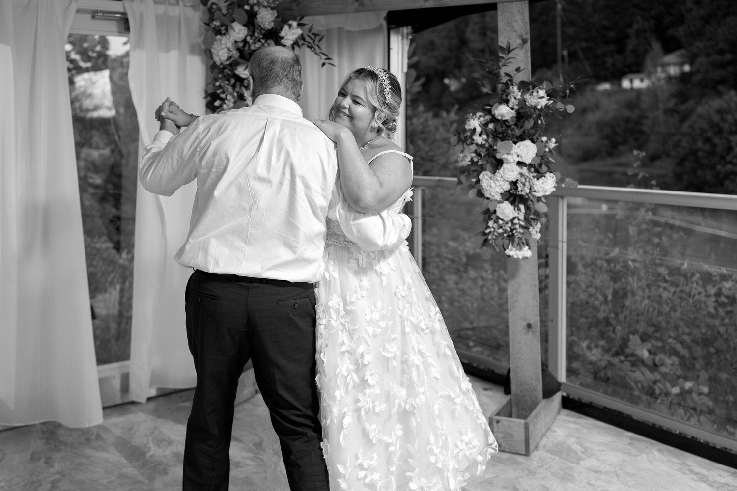 Wedding couple sharing their first dance in a bright reception venue decorated with white flowers.