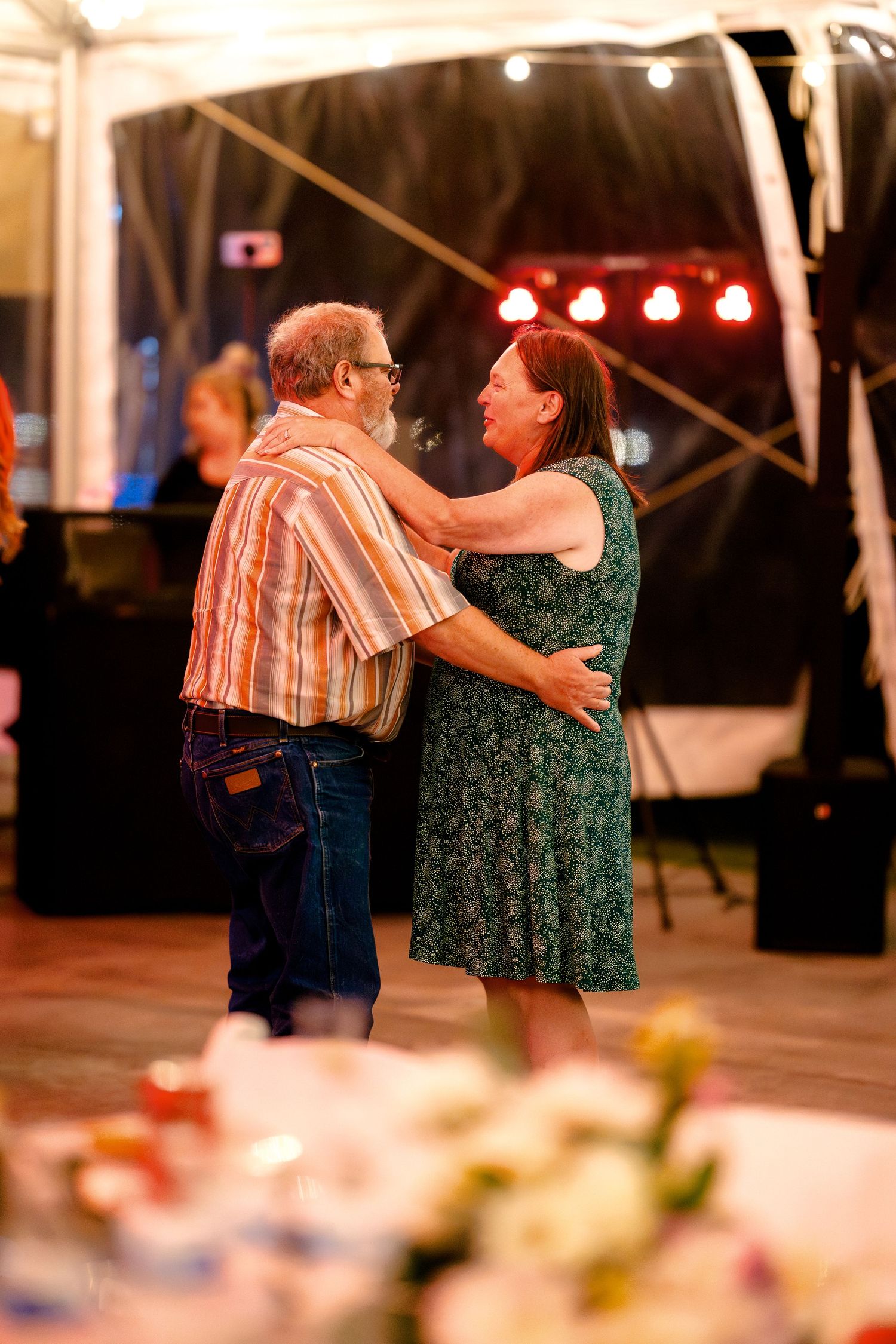 Couples dancing together at an outdoor evening event with warm lighting and floral decorations.