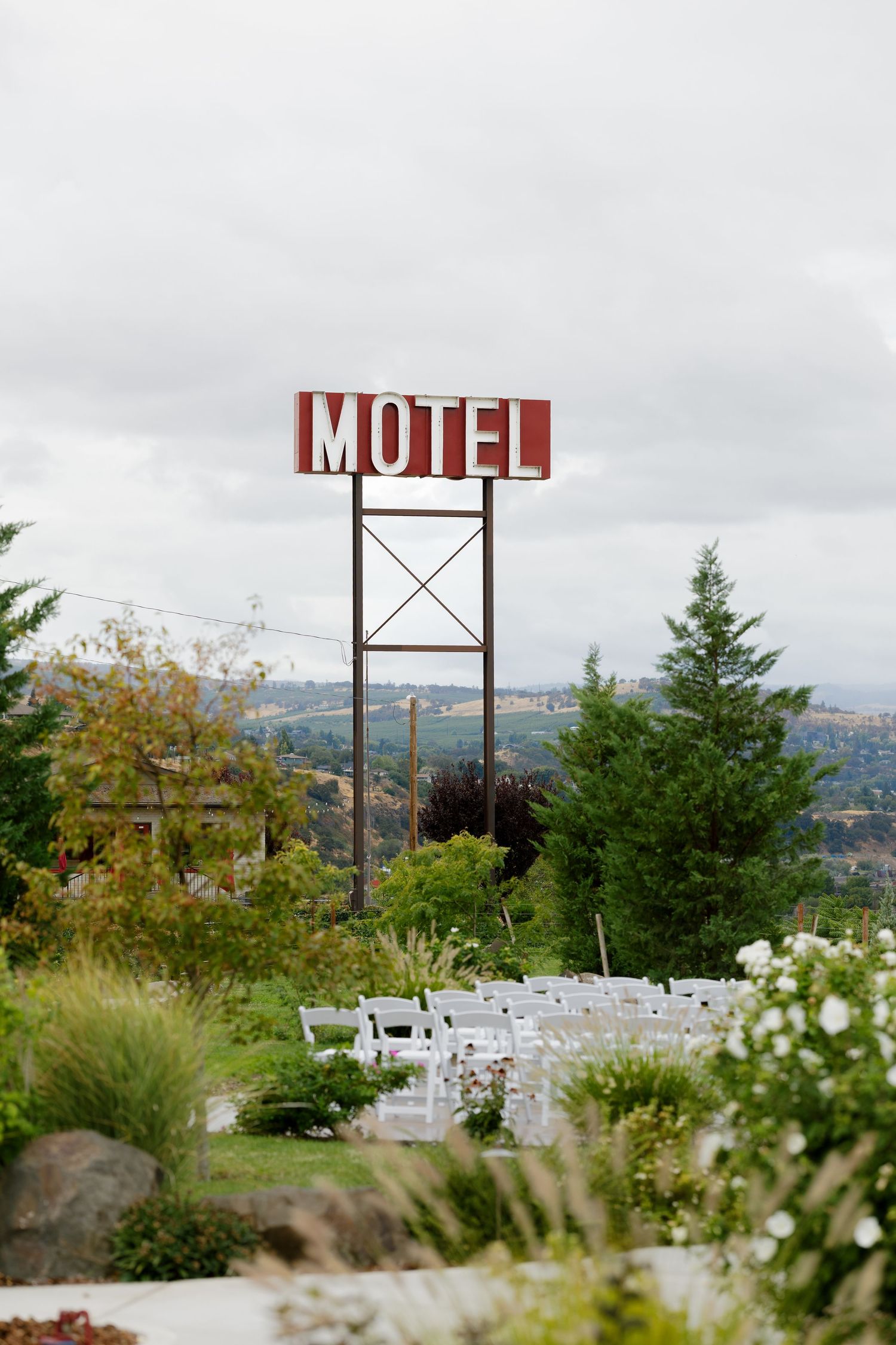 Vintage motel sign on hilltop overlooking mountain landscape with wildflowers in foreground.