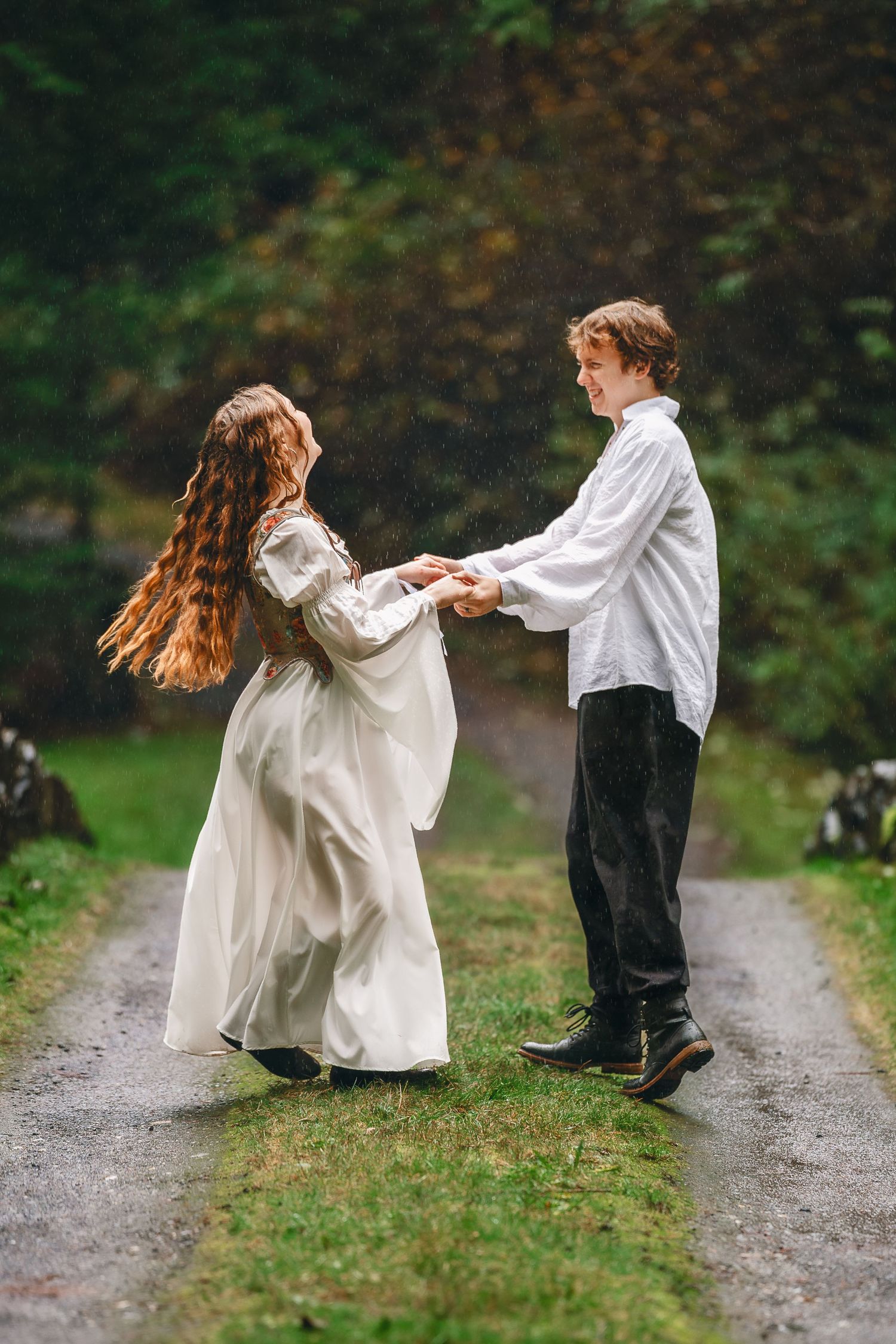 Two dancers in white and black outfits perform a graceful spinning dance sequence on a forest path.
