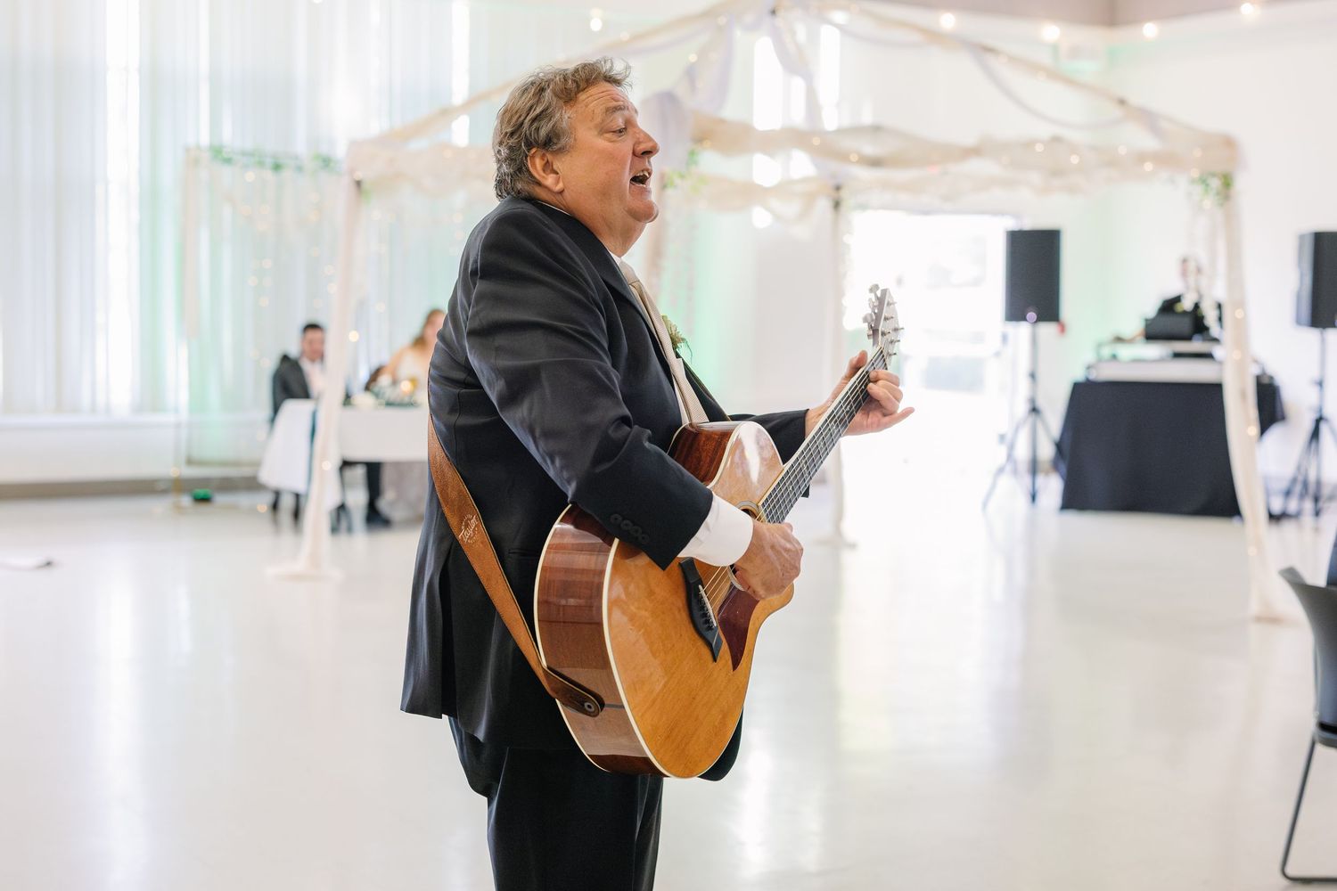 Live musician performing with guitar at indoor wedding reception.