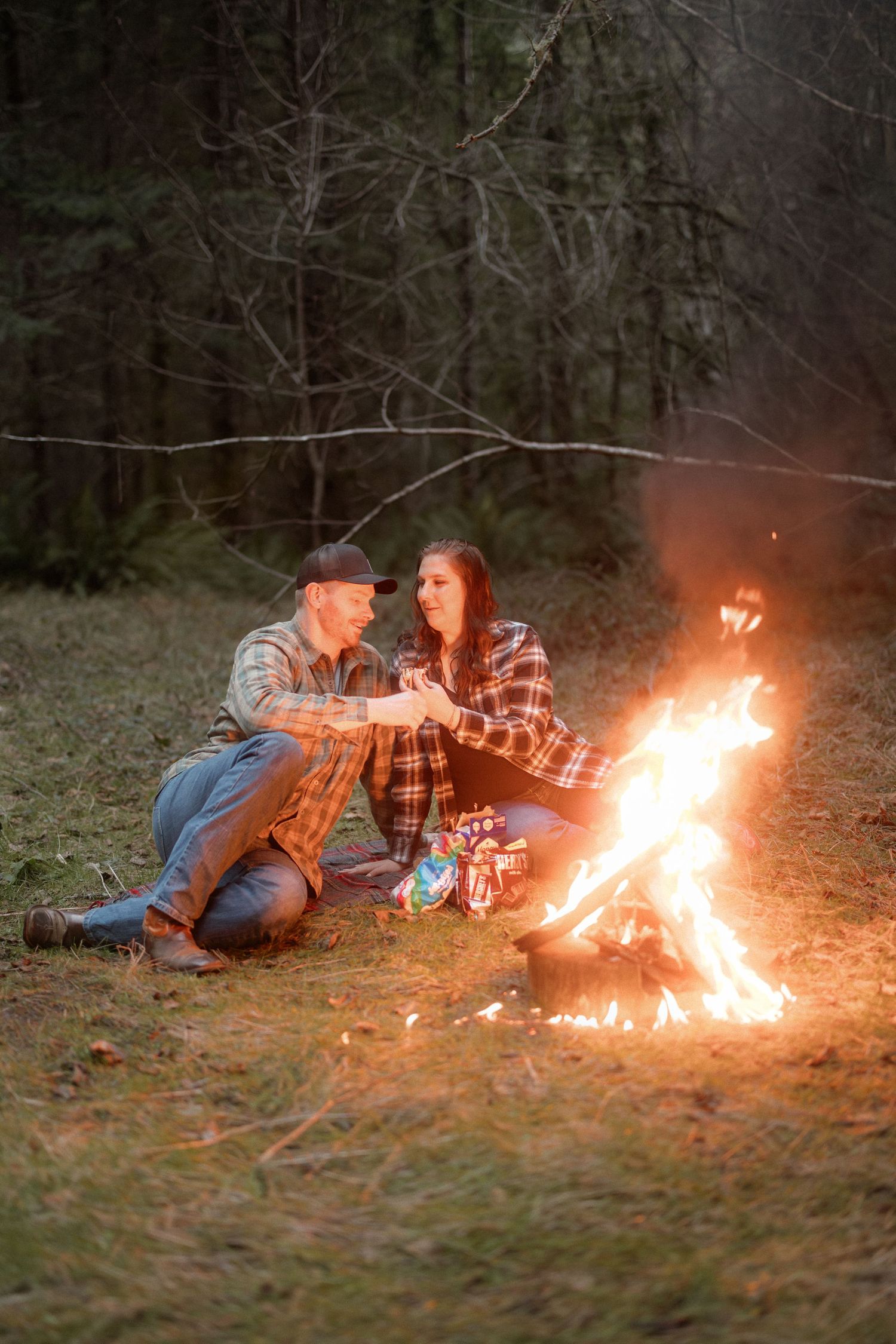 Couple relaxing by a warm campfire in the woods during an evening outdoor session.