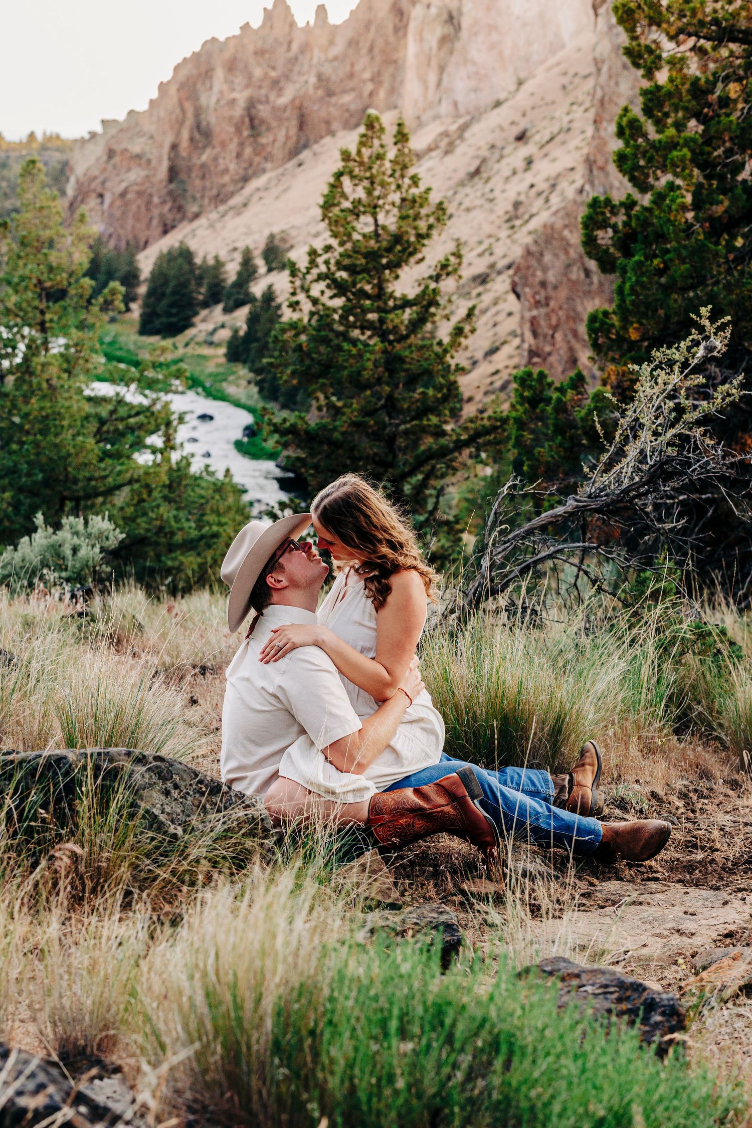 A romantic photo session in tall grass with towering rock formations in the background.