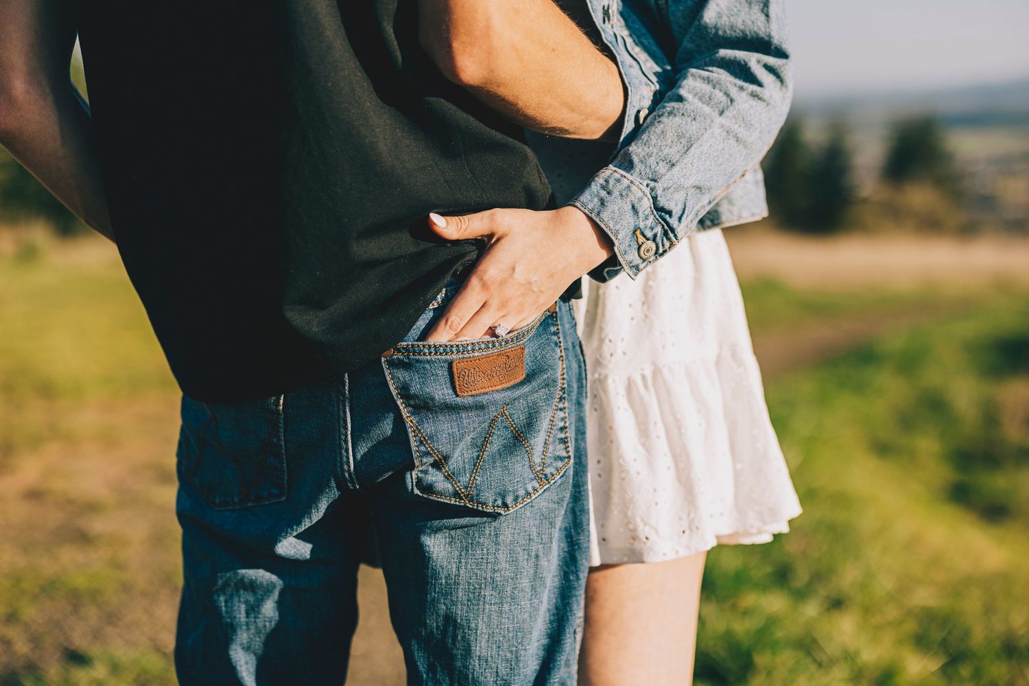 Intimate shot of a couple in casual clothing standing close together against a blurred outdoor background.
