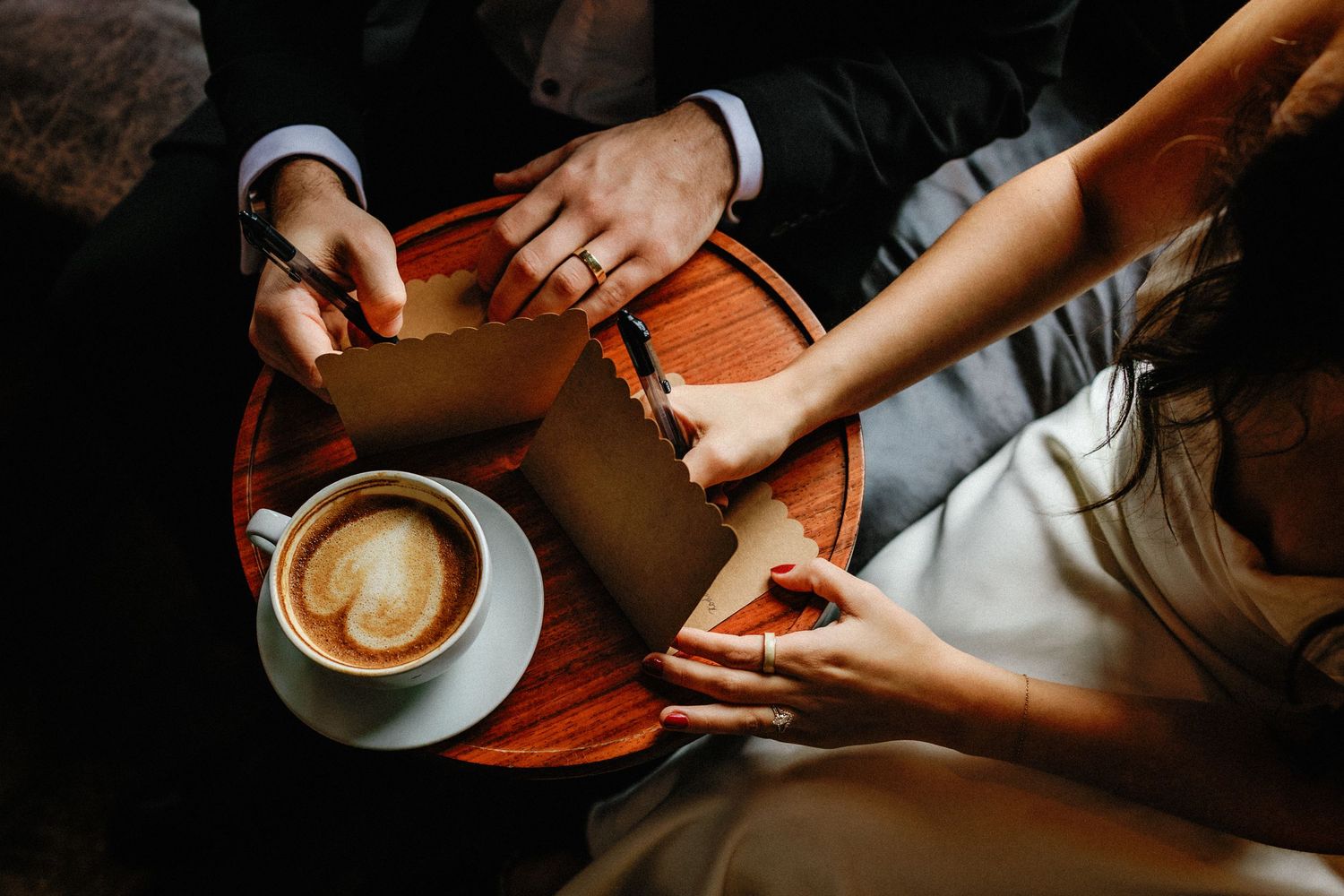 Hands holding and preparing various coffee drinks with latte art in a cafe setting.