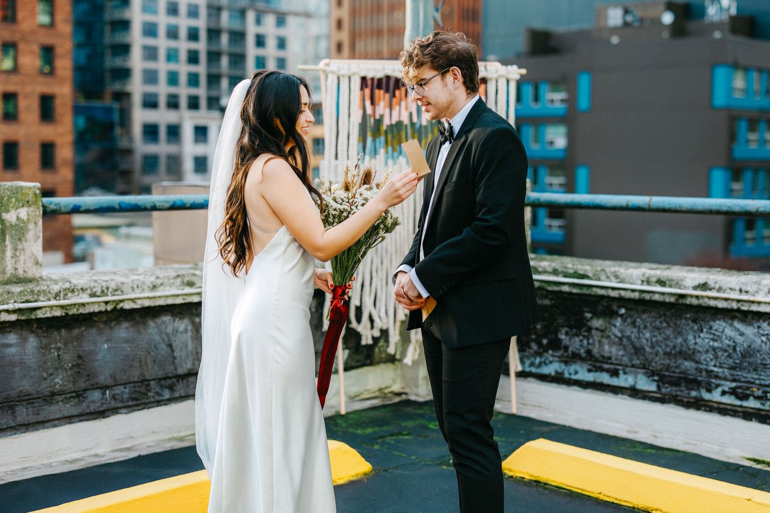 Couple sharing intimate moment on urban rooftop with city buildings in background.