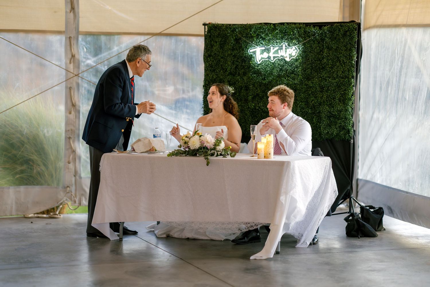 Elegant wedding reception setup with white draping and tables arranged under a tent structure.