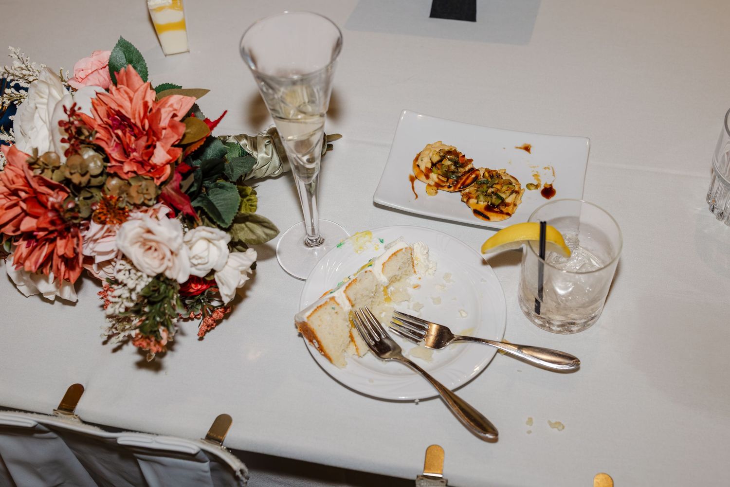 Wedding reception table with floral centerpiece, champagne flute, and finished dinner plate.