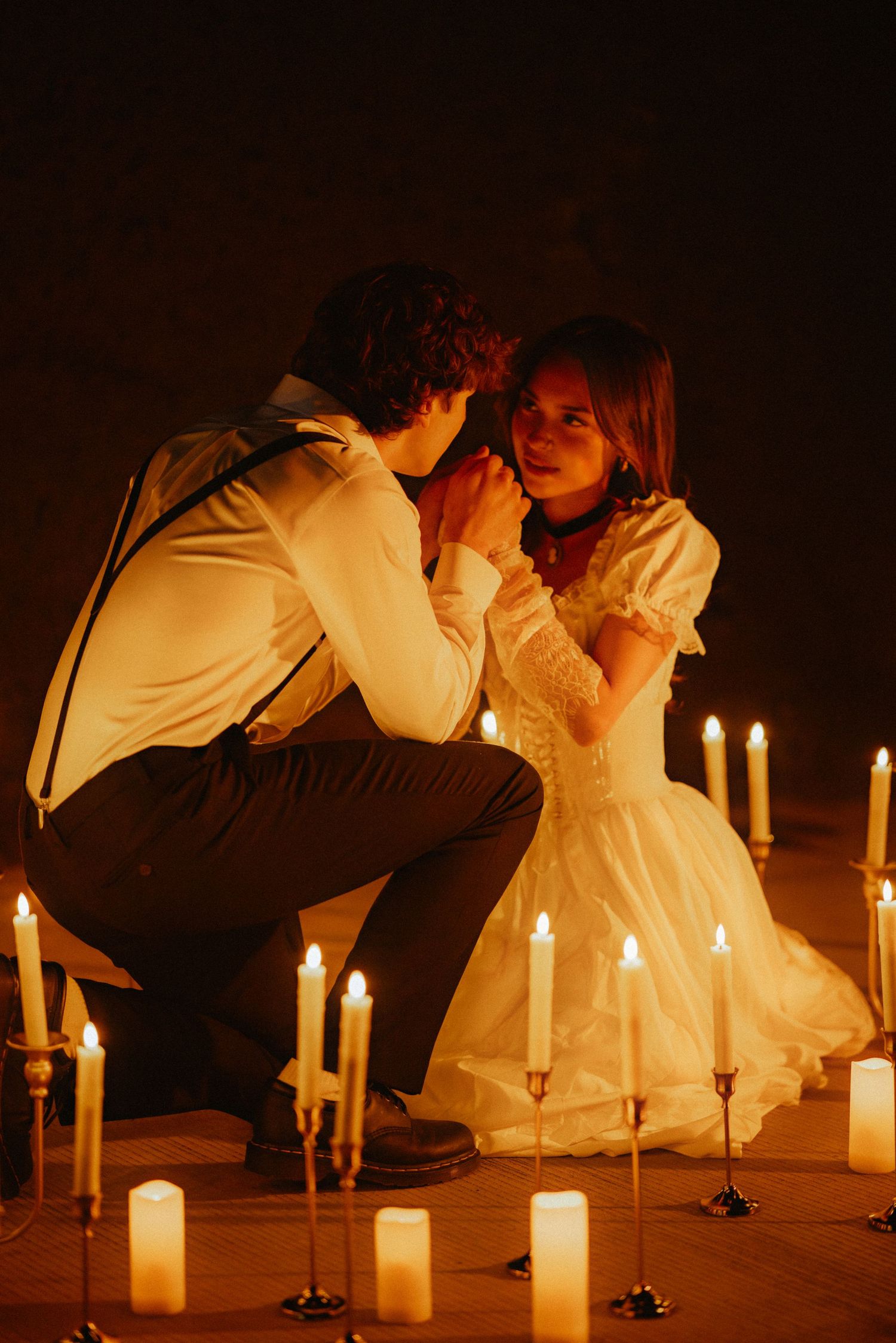 A romantic candlelit scene with a couple in vintage attire surrounded by glowing white candles.