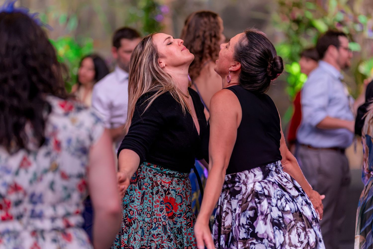 Two women laugh and dance together joyfully on the wedding reception dance floor.