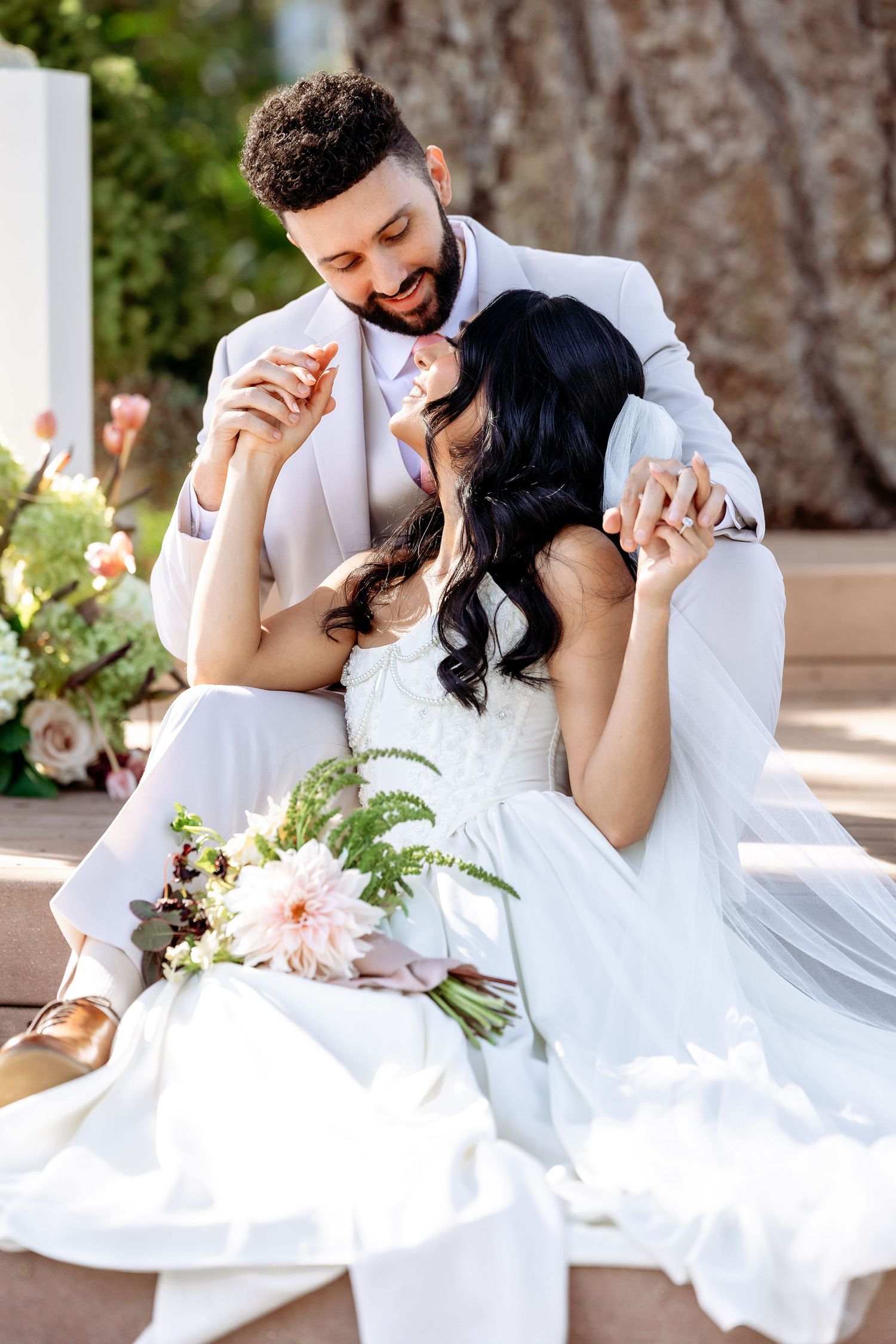 Joyful wedding couple shares laughs while sitting together at decorated outdoor reception.