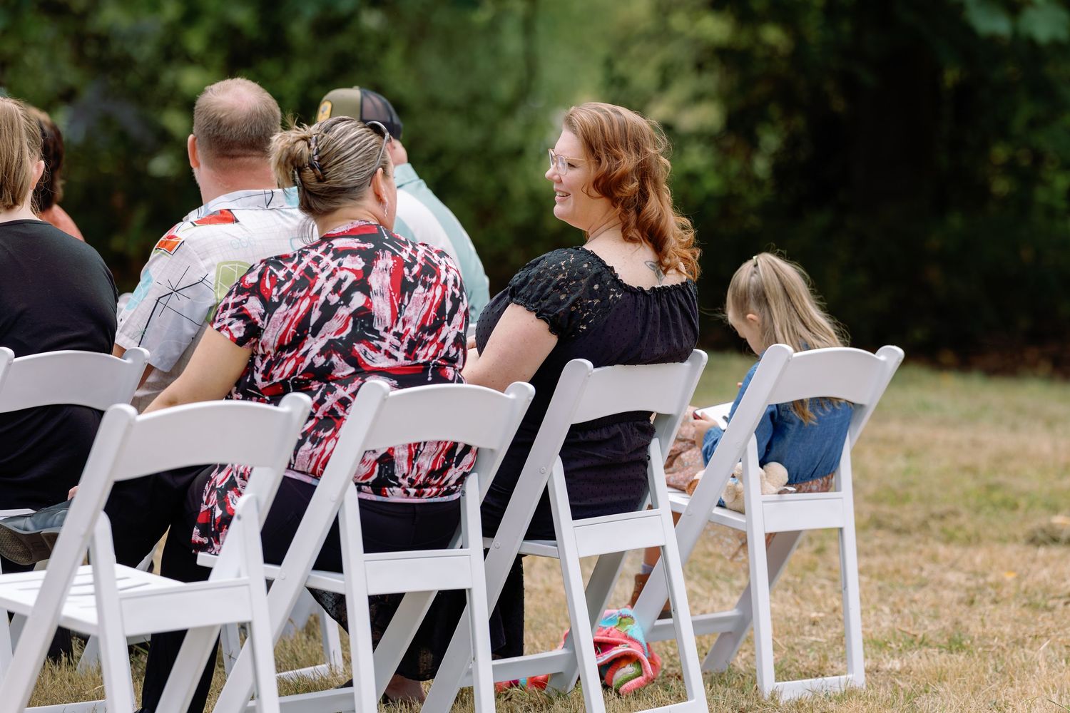 White folding chairs arranged in rows on grass for an outdoor wedding ceremony.