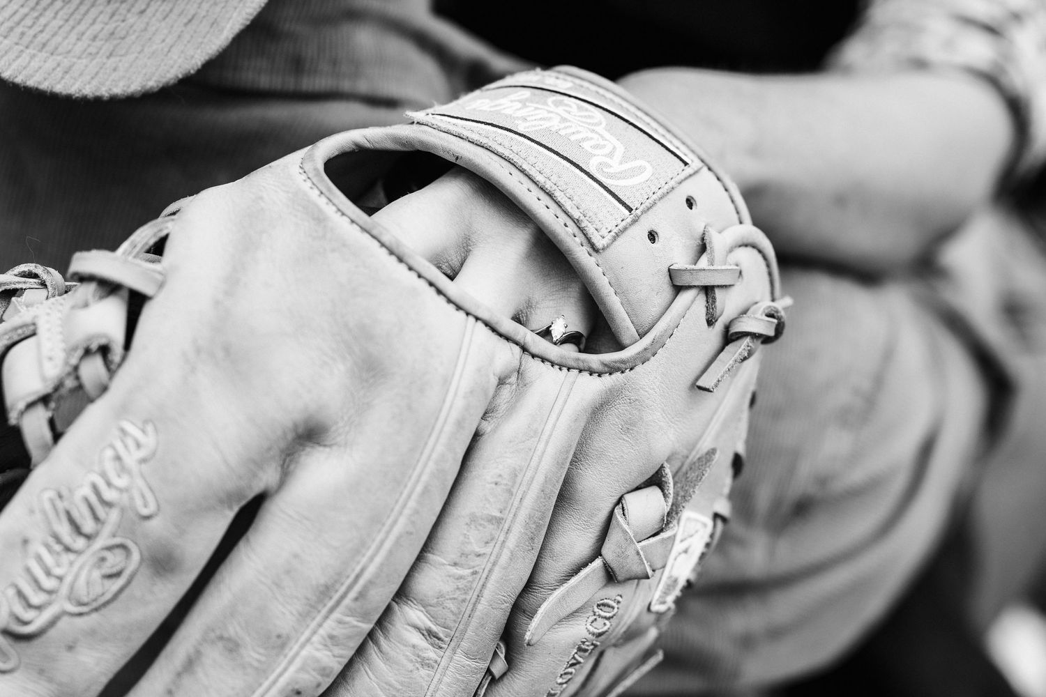 Close-up black and white view of a leather baseball glove with stitching details and webbing pattern.
