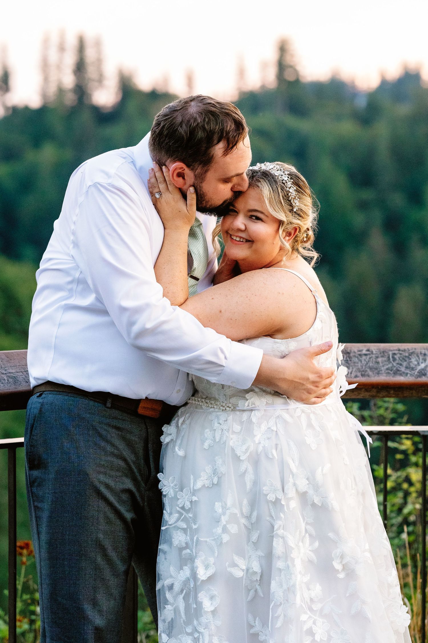 A romantic moment shared between a couple on an outdoor terrace with lush greenery in the background.