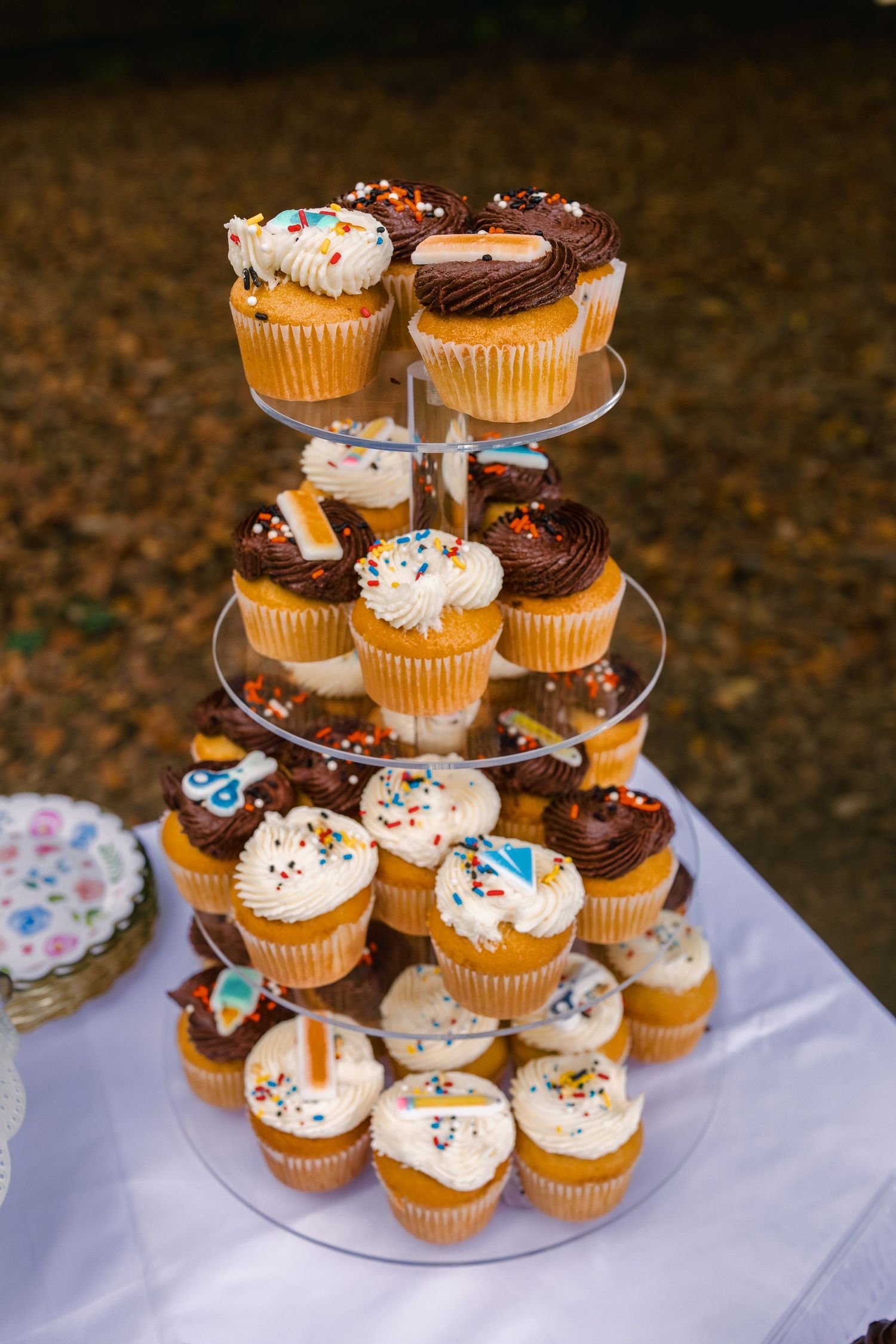 Tiered display of chocolate and vanilla cupcakes decorated with colorful sprinkles and frosting at a party.