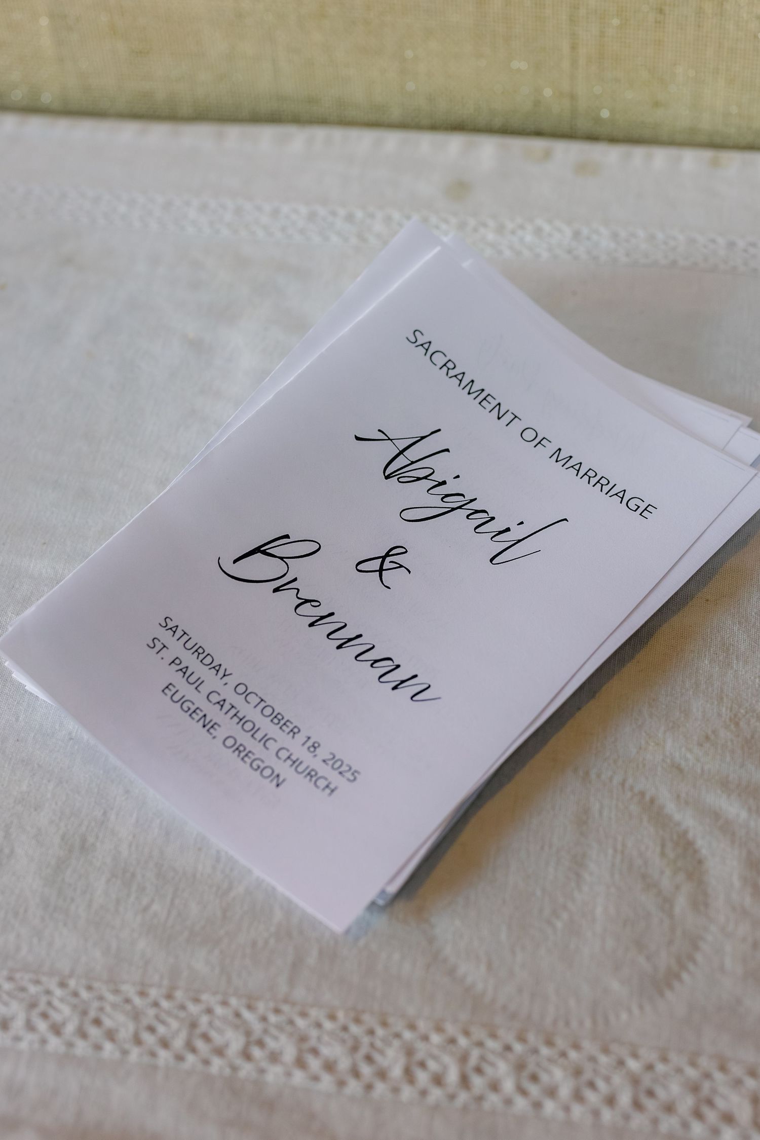 Wedding place cards with elegant calligraphy displayed on white textured tablecloth.