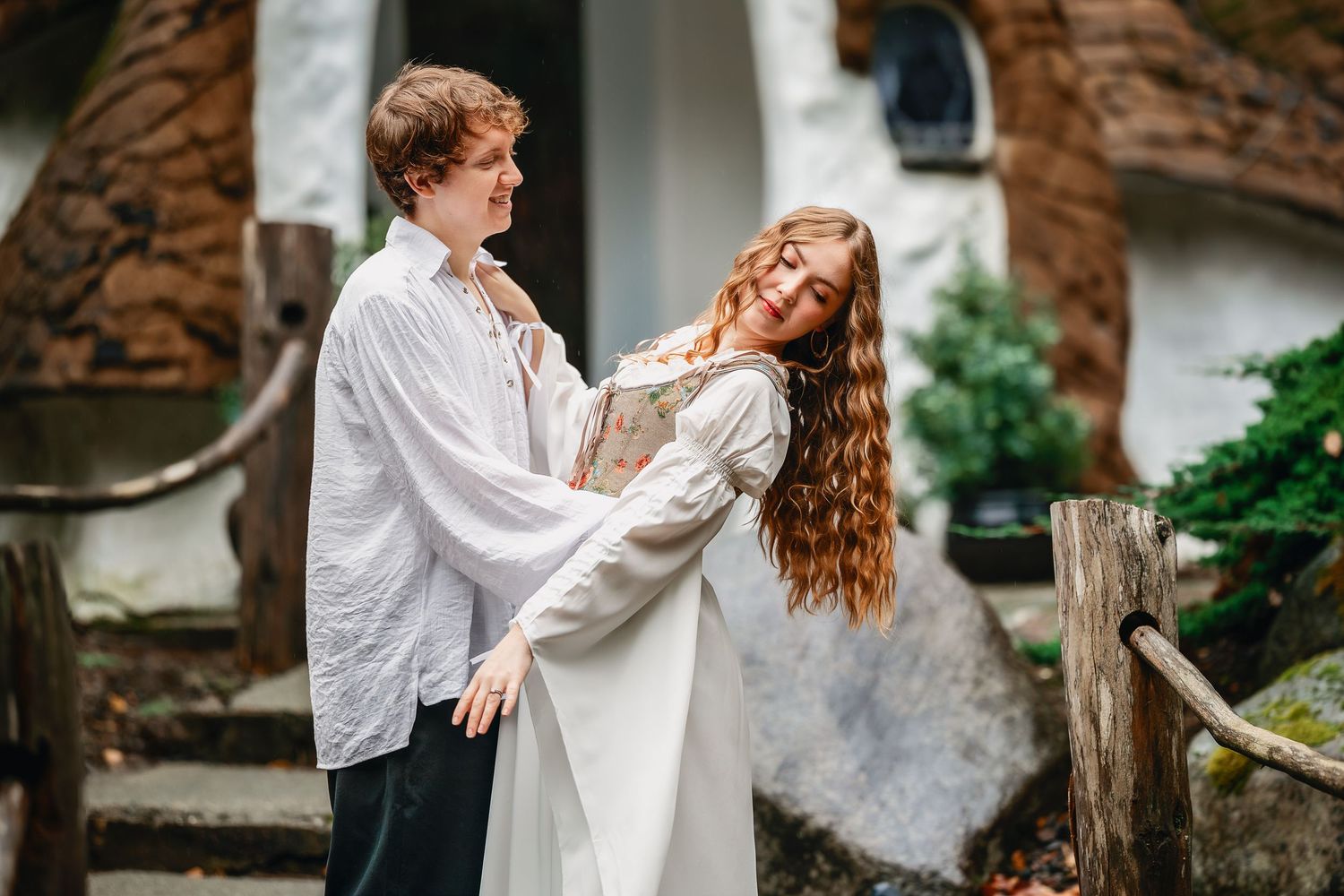 A romantic couple in white clothing dances and embraces in an outdoor garden setting.