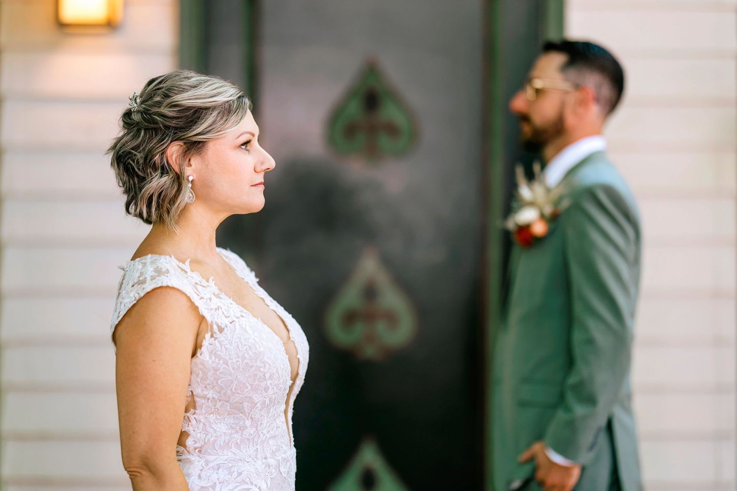 A couple shares intimate moments in front of a white house with a decorative green door.