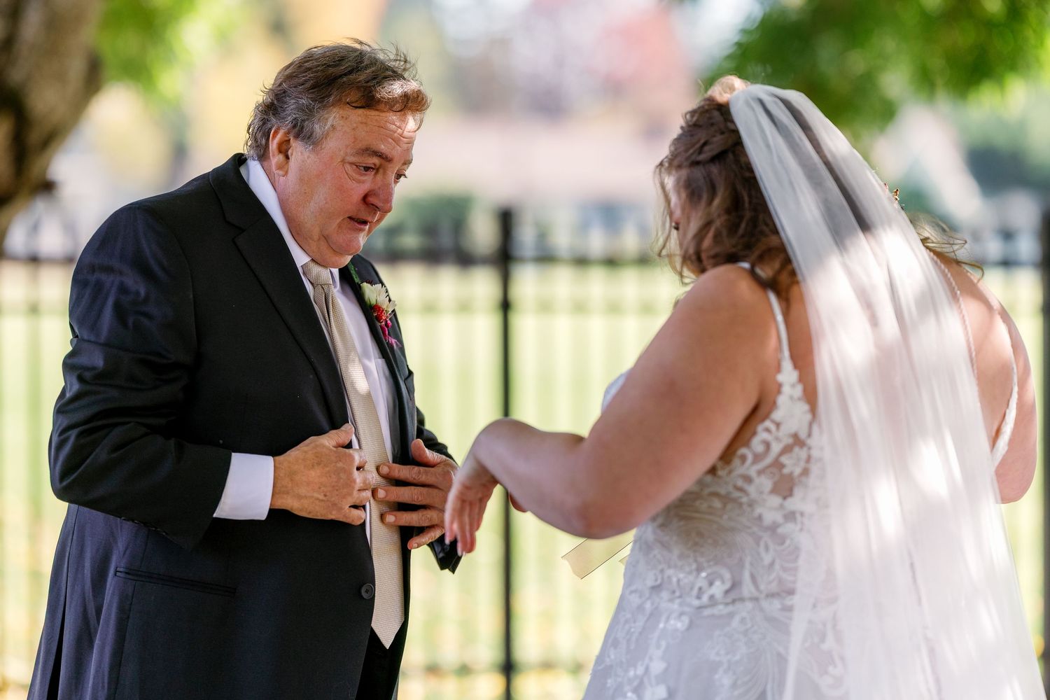 An outdoor wedding ceremony moment under trees with guests in attendance.