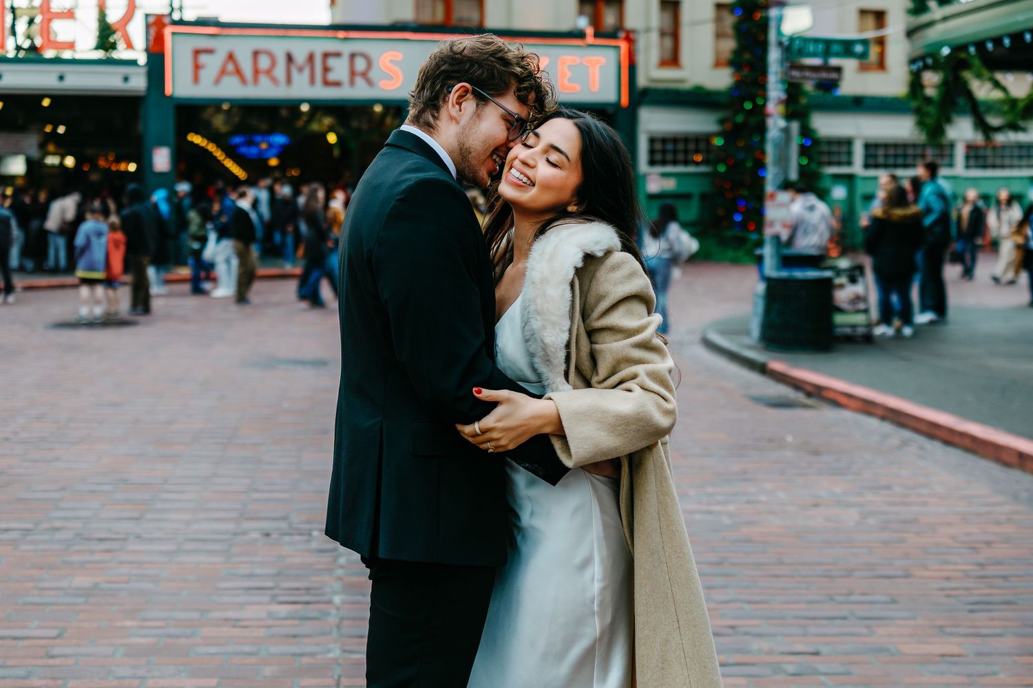 Romantic couple embracing in front of an urban storefront with 'FARMER' signage visible.