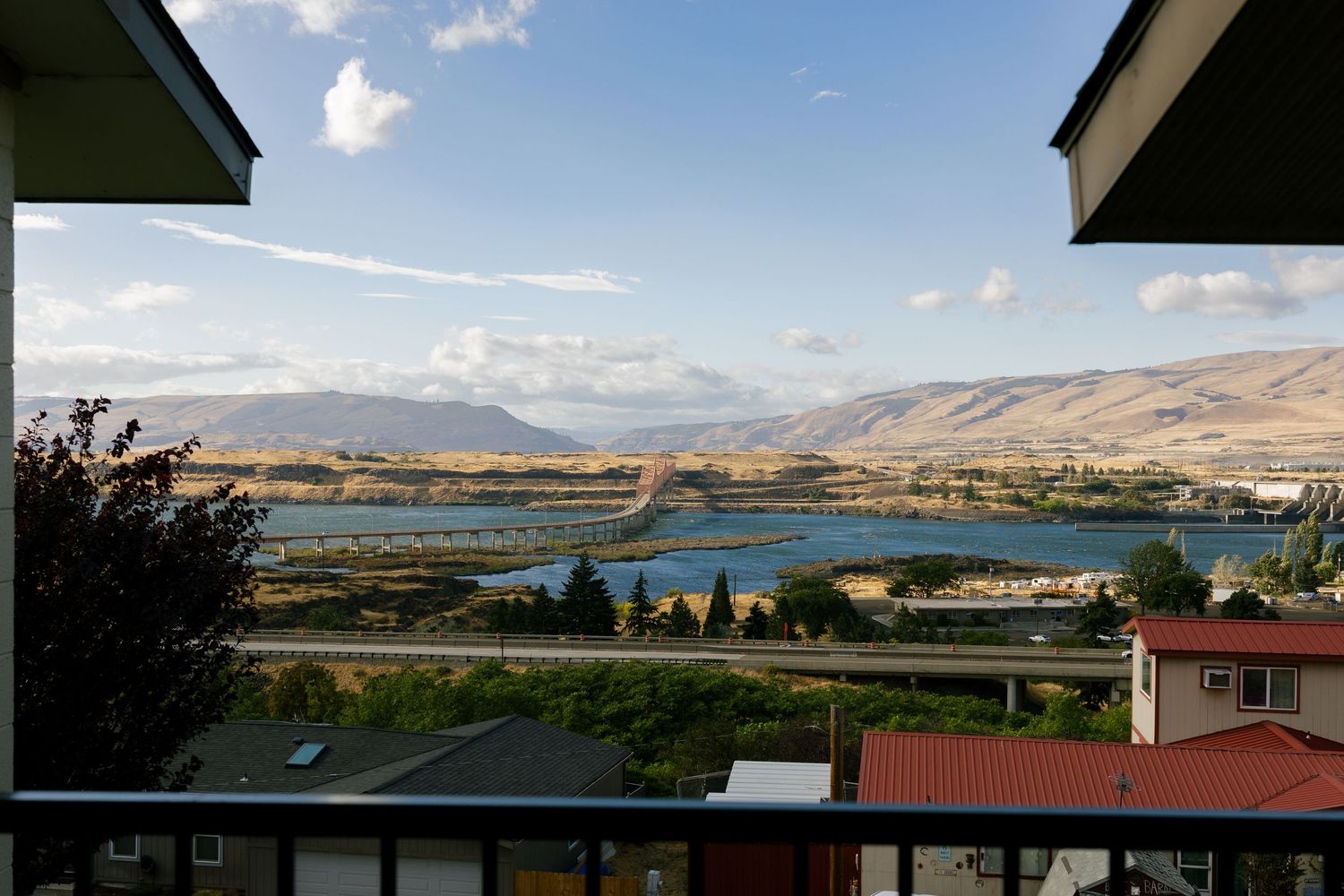 Panoramic landscape view of mountains and lake under blue sky with white clouds.
