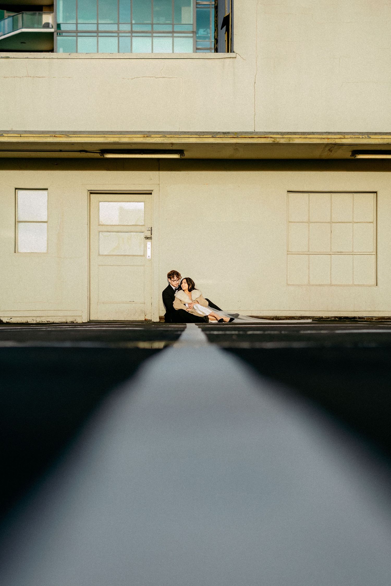 A minimalist architectural sequence showing a figure reclining against a modern building exterior.