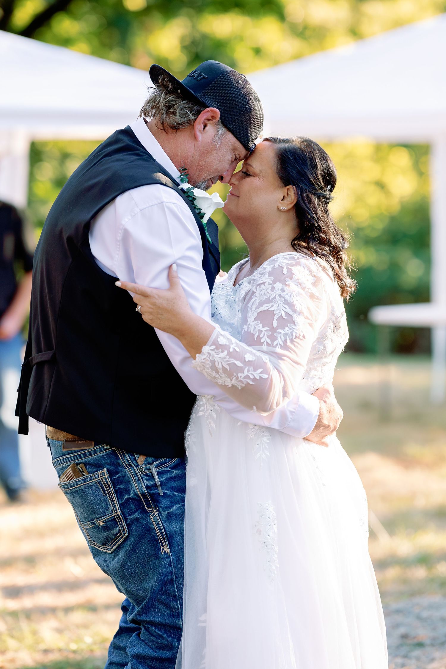 A tender moment between newlyweds sharing their first dance at an outdoor wedding reception.