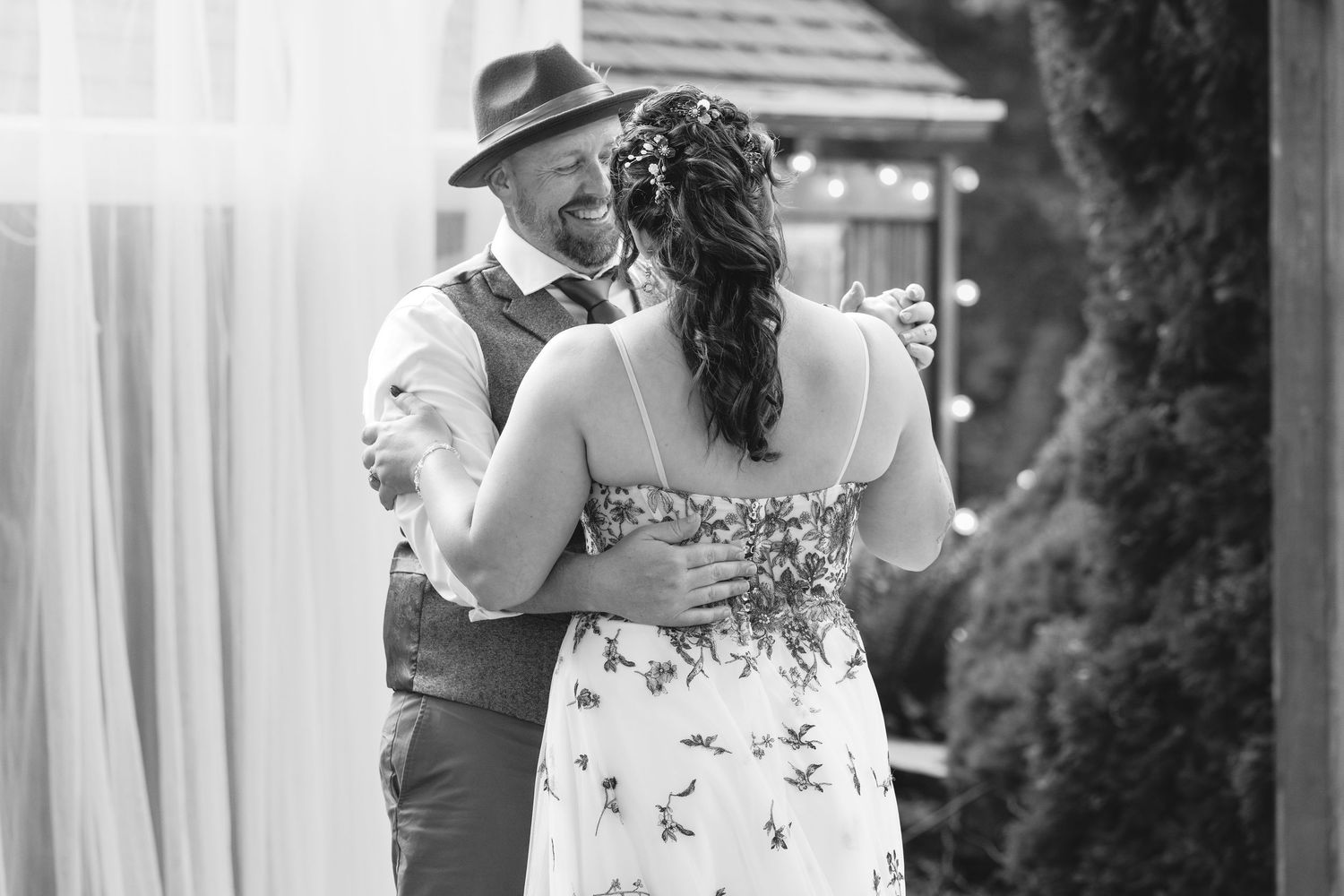 Black and white romantic moment captured during an outdoor wedding celebration.
