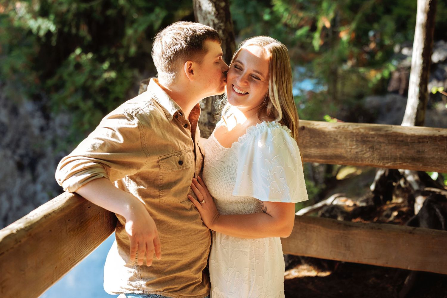 A romantic couple shares a tender moment in sunlit outdoor setting wearing casual attire.