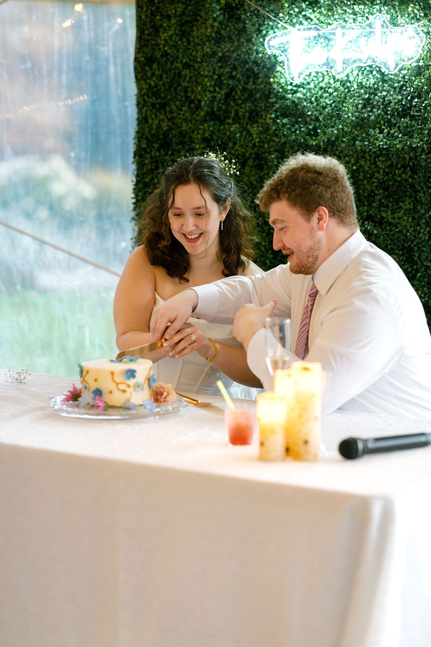 A couple shares a romantic moment at a restaurant table with drinks and plates visible.