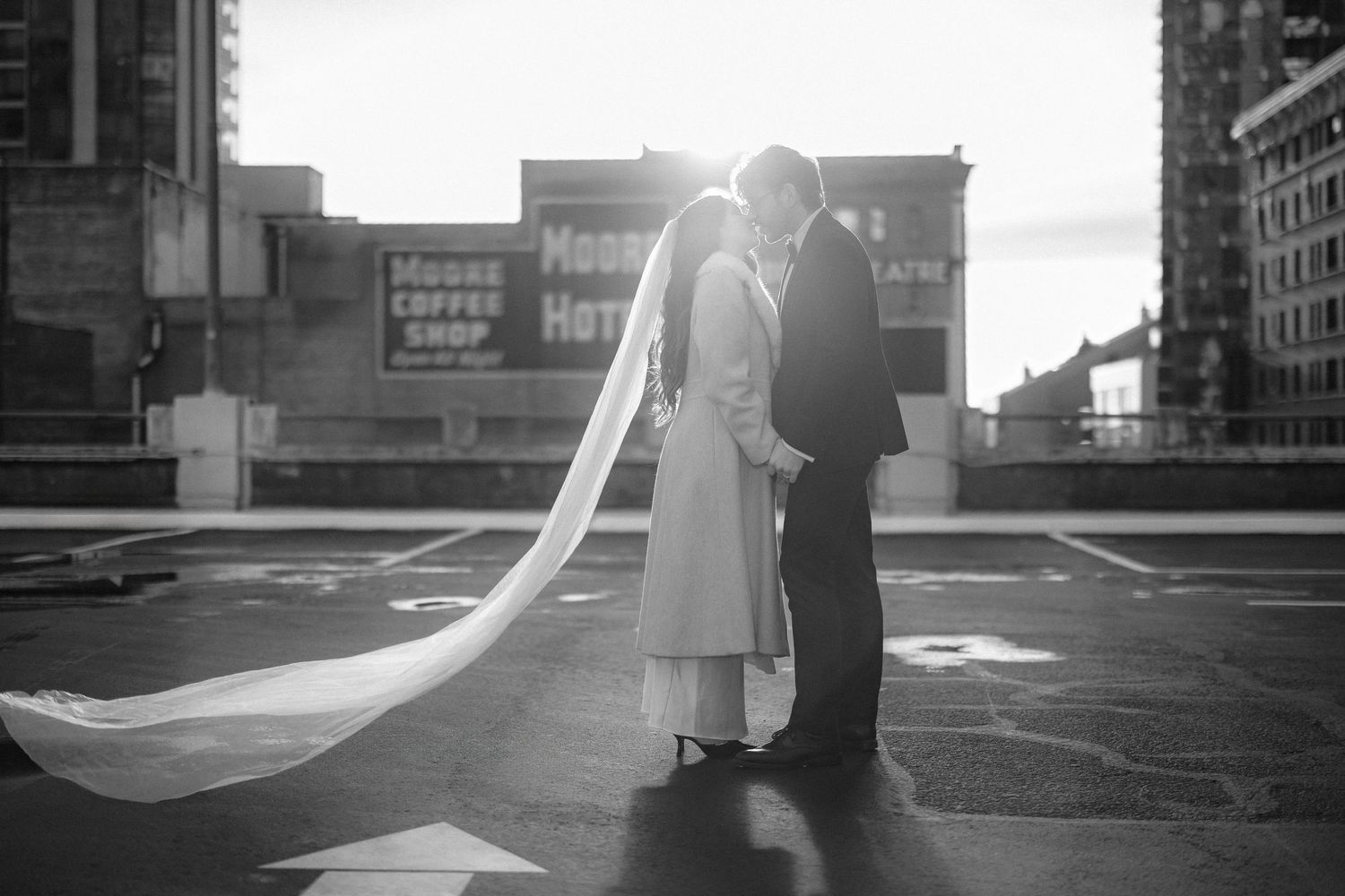 A black and white wedding photo series showing a couple embracing in various romantic poses on a rooftop.