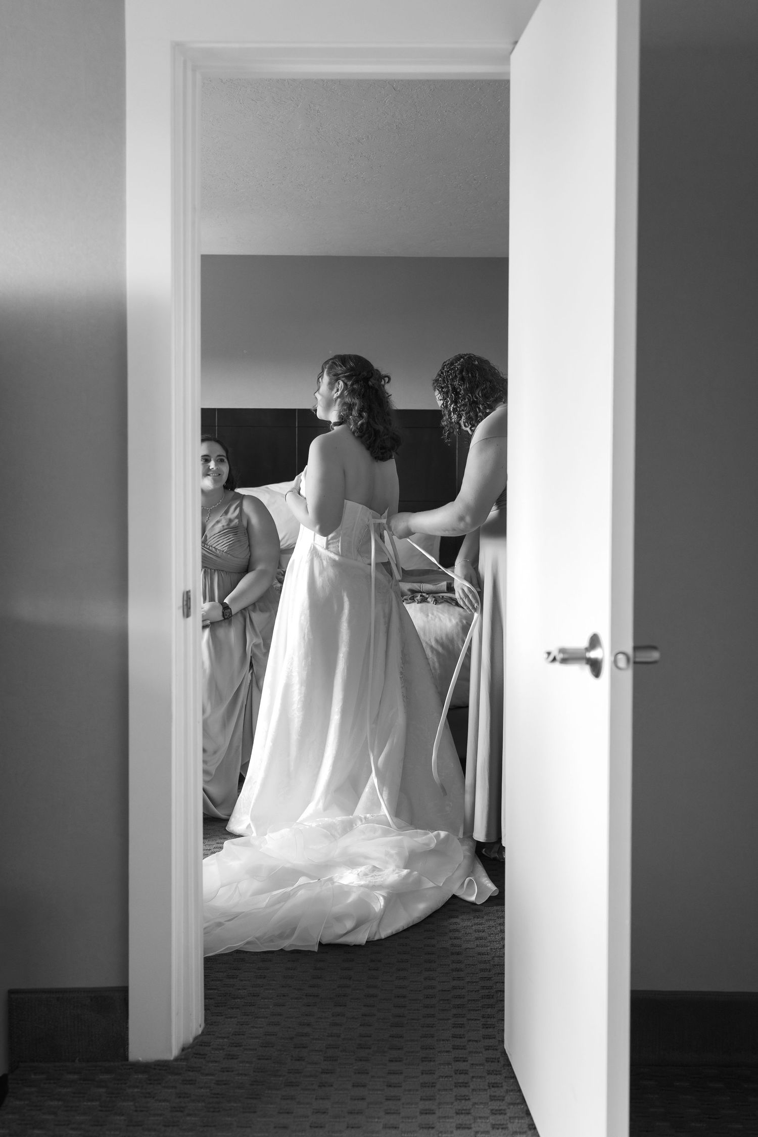 A series of black and white photos showing figures in white fabric moving through a hallway with dramatic lighting.