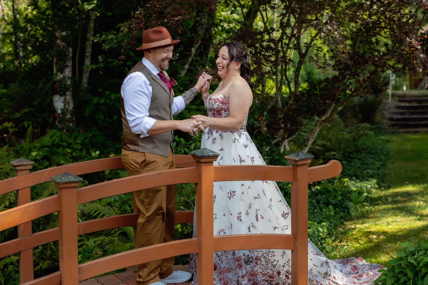Wedding couple shares intimate moment on wooden bridge in lush garden setting.