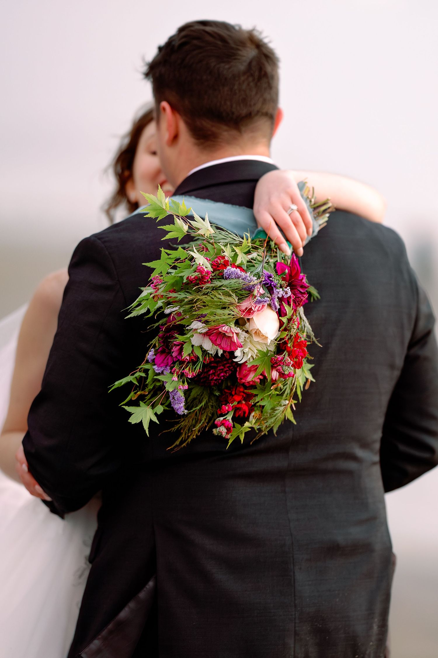 A series of photos showing a red and green floral boutonniere pinned to the back of a black suit jacket.