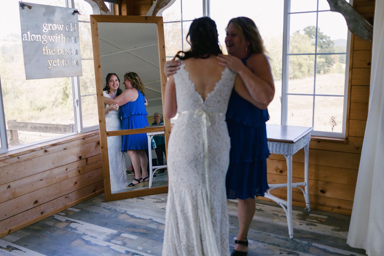 A panoramic view of a rustic wooden barn interior with wedding decorations and guests mingling.