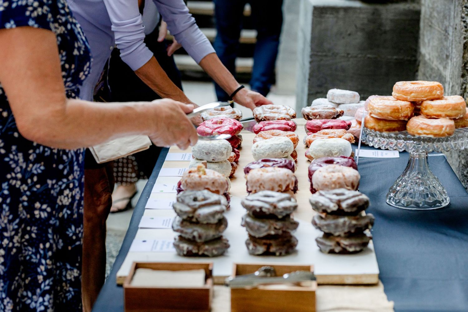 Assorted decorated donuts and pastries displayed on a table at a wedding dessert station.