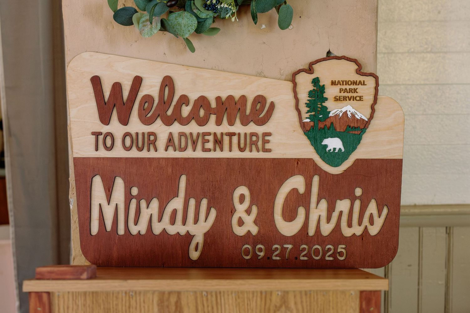 A rustic wooden welcome sign featuring a National Park Service logo and wedding date.