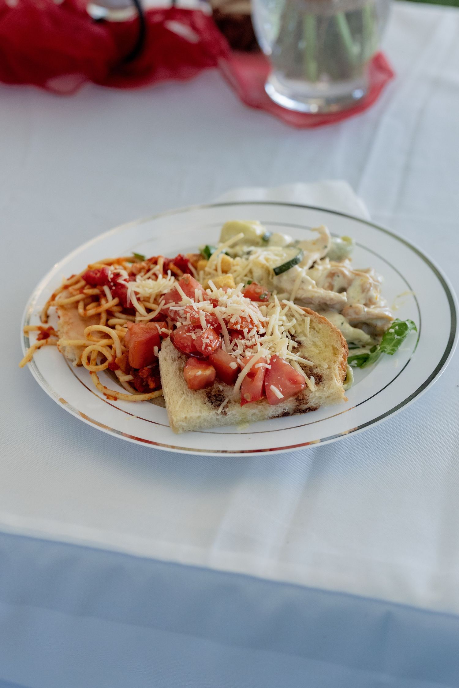 Plates of pasta with red sauce and grated cheese served on white tablecloths at an elegant dinner setting.