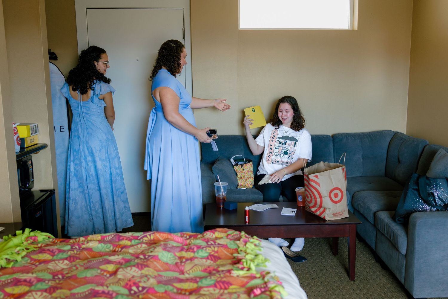 Wedding party members in light blue dresses preparing in a sunlit room.