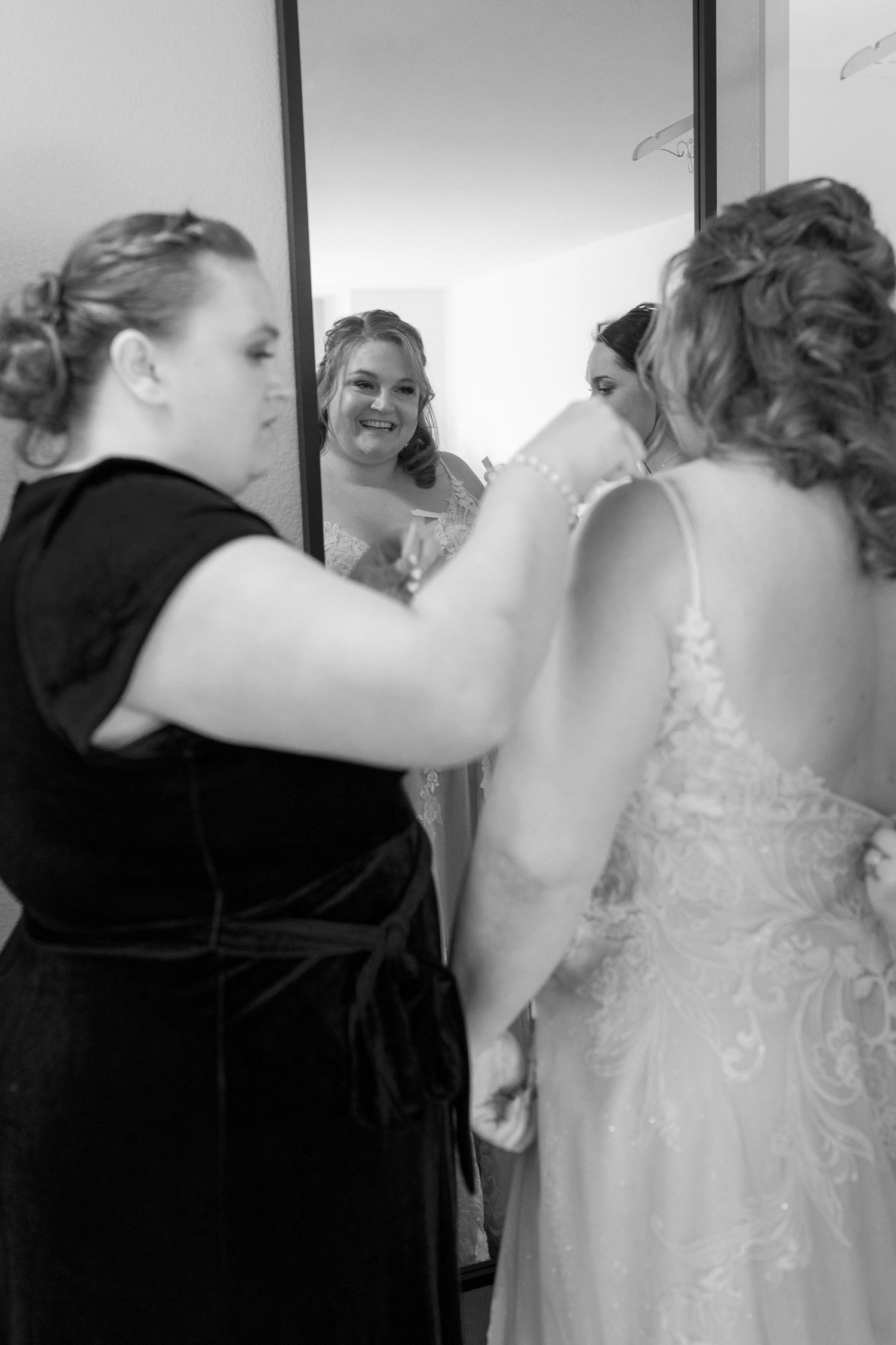 Black and white sequence showing a wedding dress being buttoned up during bridal preparations.